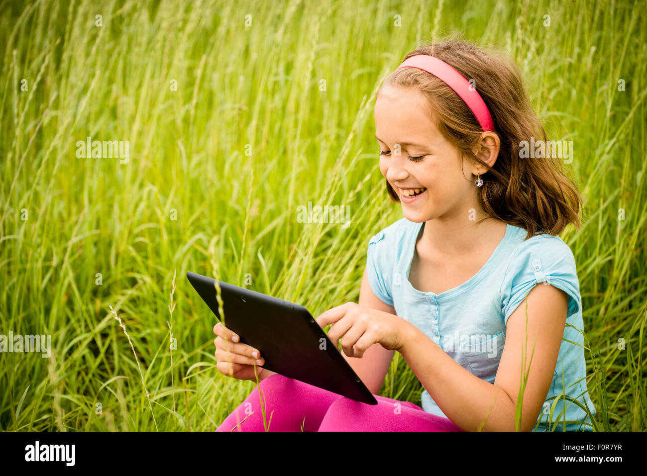 Smiling child working with tablet outdoor in nature Stock Photo