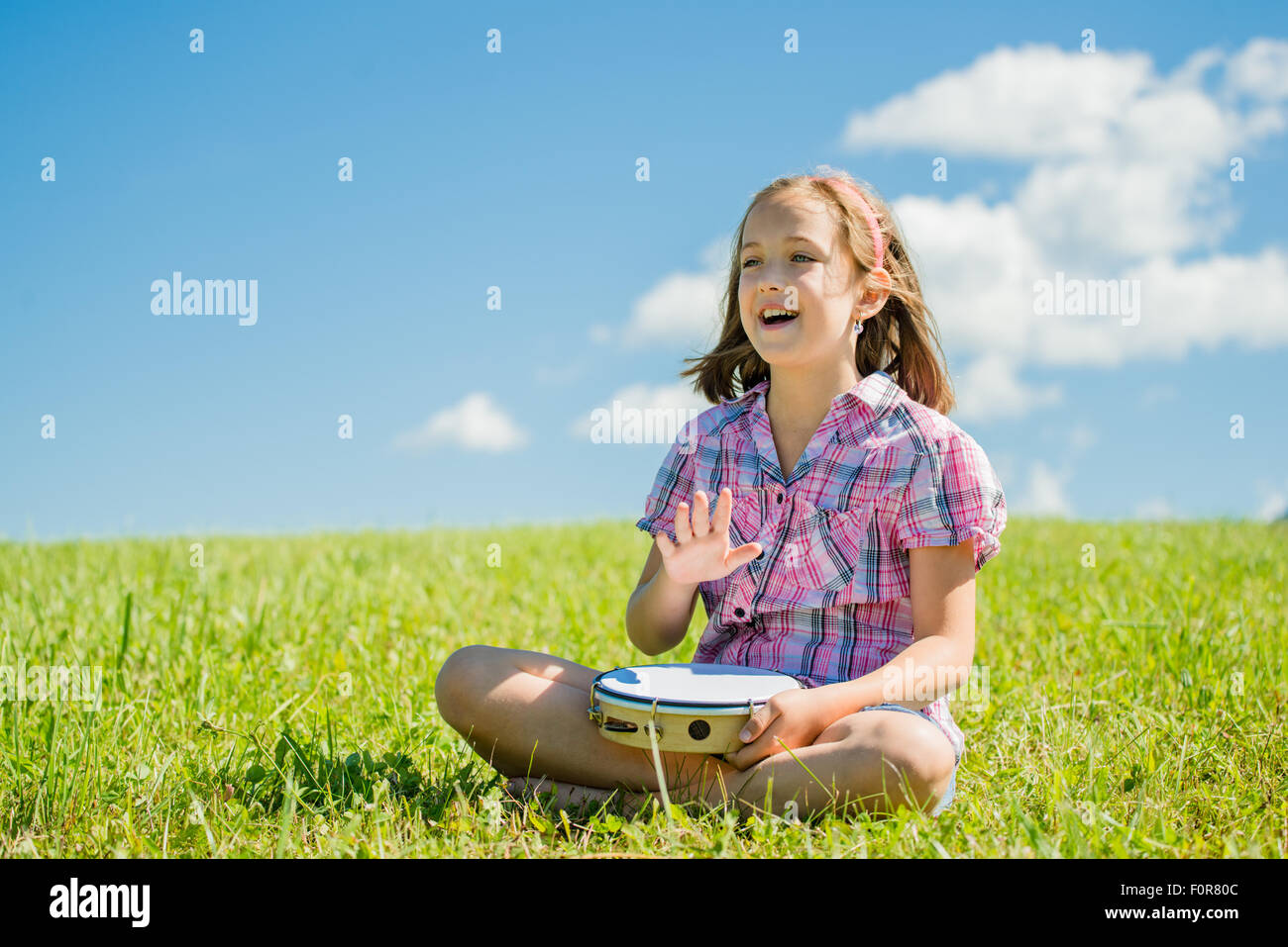 Cute teen girl playing tambourine and singing - outdoor in nature Stock Photo