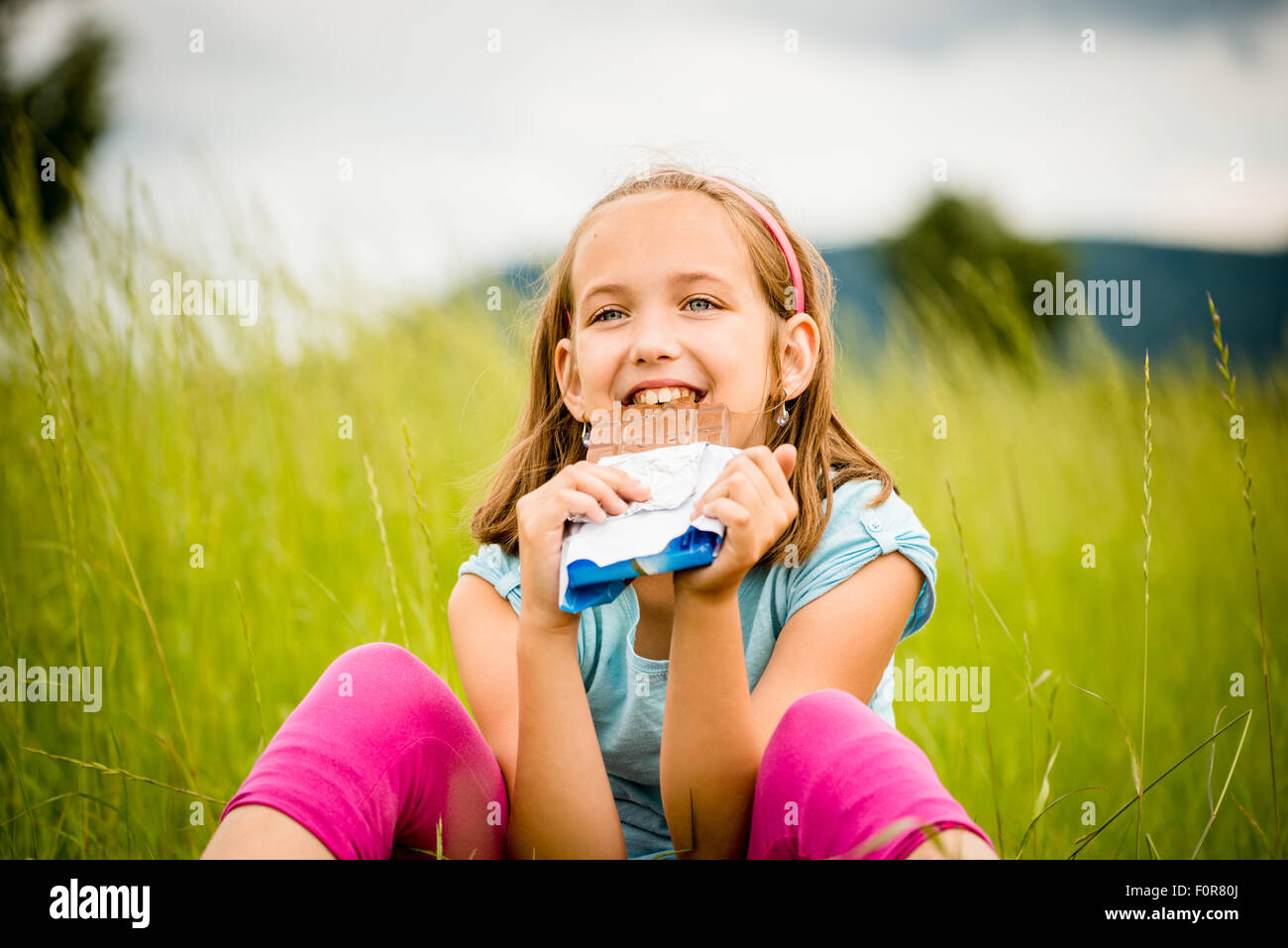 Child eating and relishing chocolate - outdoor in nature Stock Photo