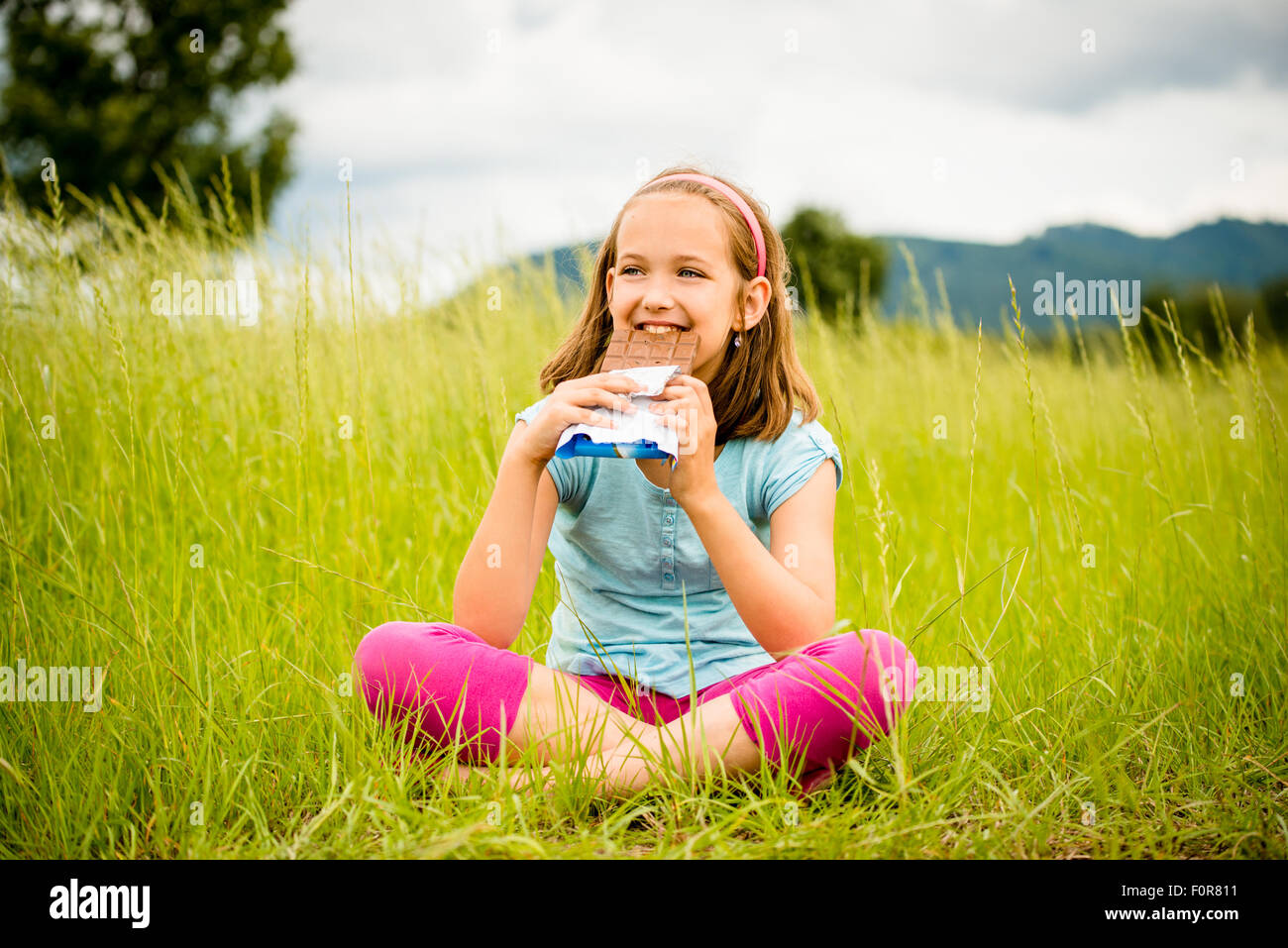 Child eating and relishing chocolate - outdoor in nature Stock Photo