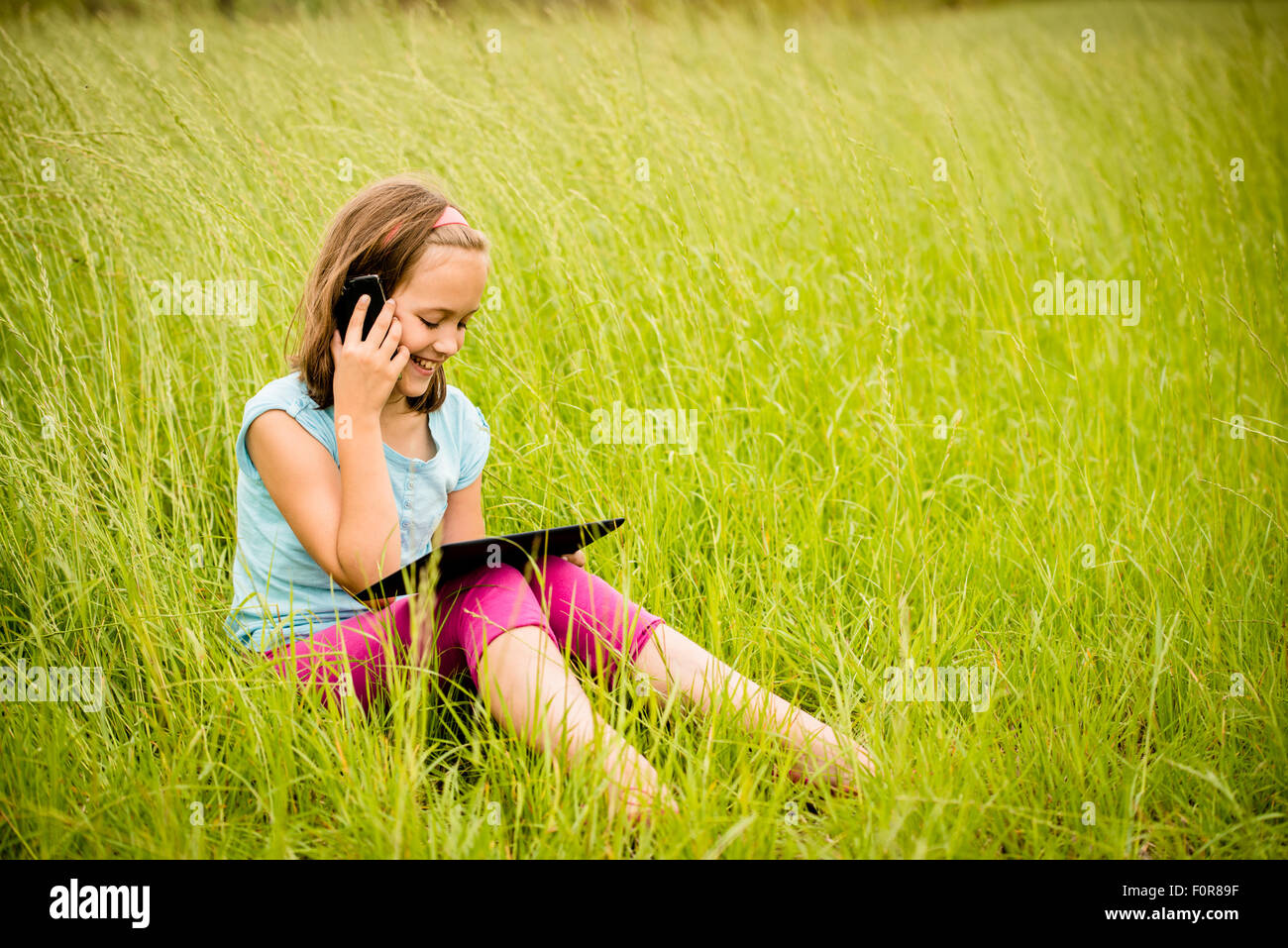 Smiling child watching movie on tablet outdoor in nature Stock Photo