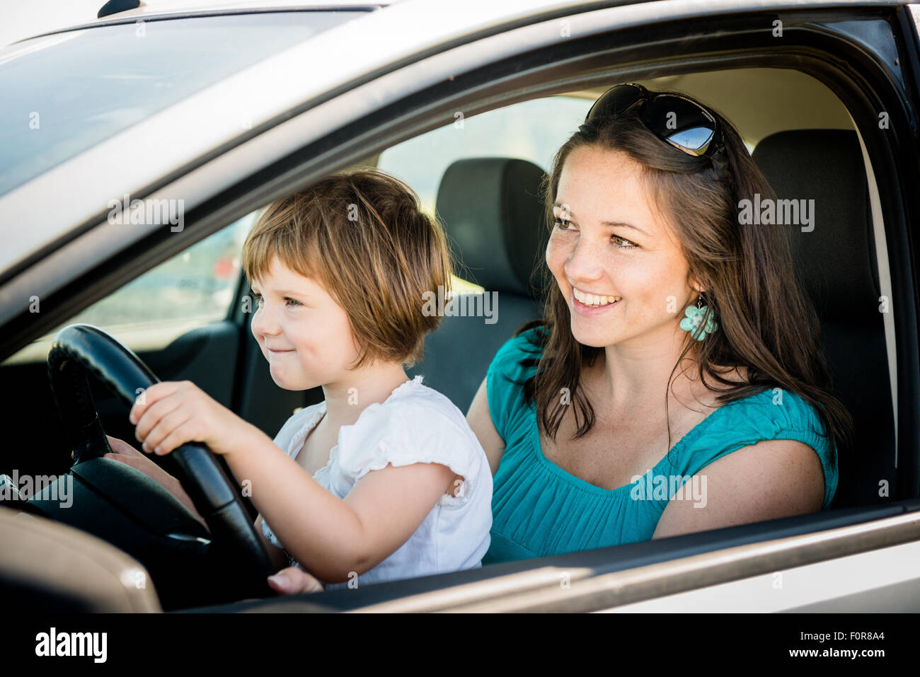 Mother and child pretend driving car sitting both on front driver seat Stock Photo