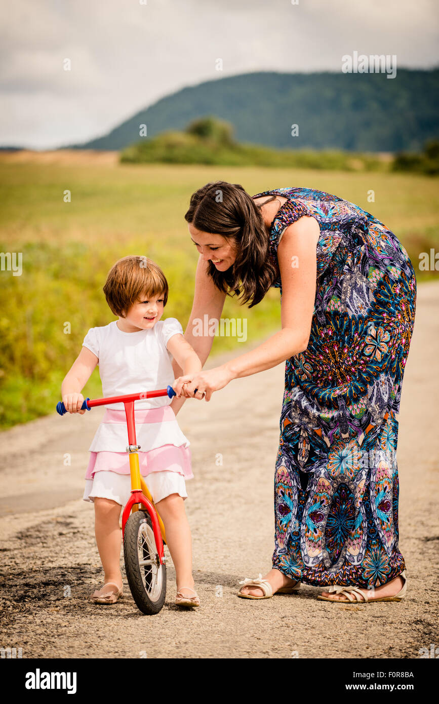 Mother teaching her child riding her firs bike in nature Stock Photo