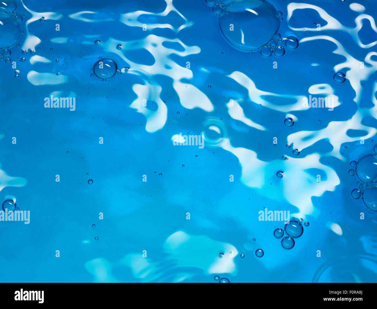 A close up, vertical shot of fresh blue water with reflections and bubbles with copy space for the designer Stock Photo
