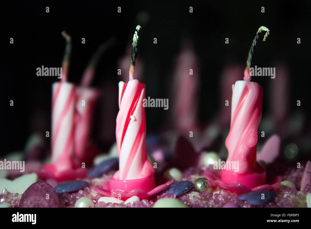 Pink and white swirly birthday candles on top of a cake after being