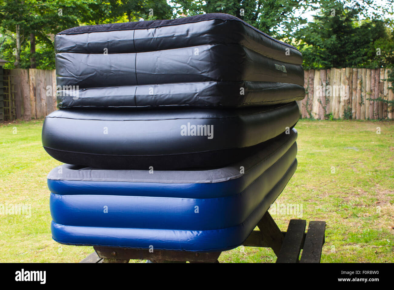 Three different air beds piled on top of each other on top of a picnic bench. Stock Photo