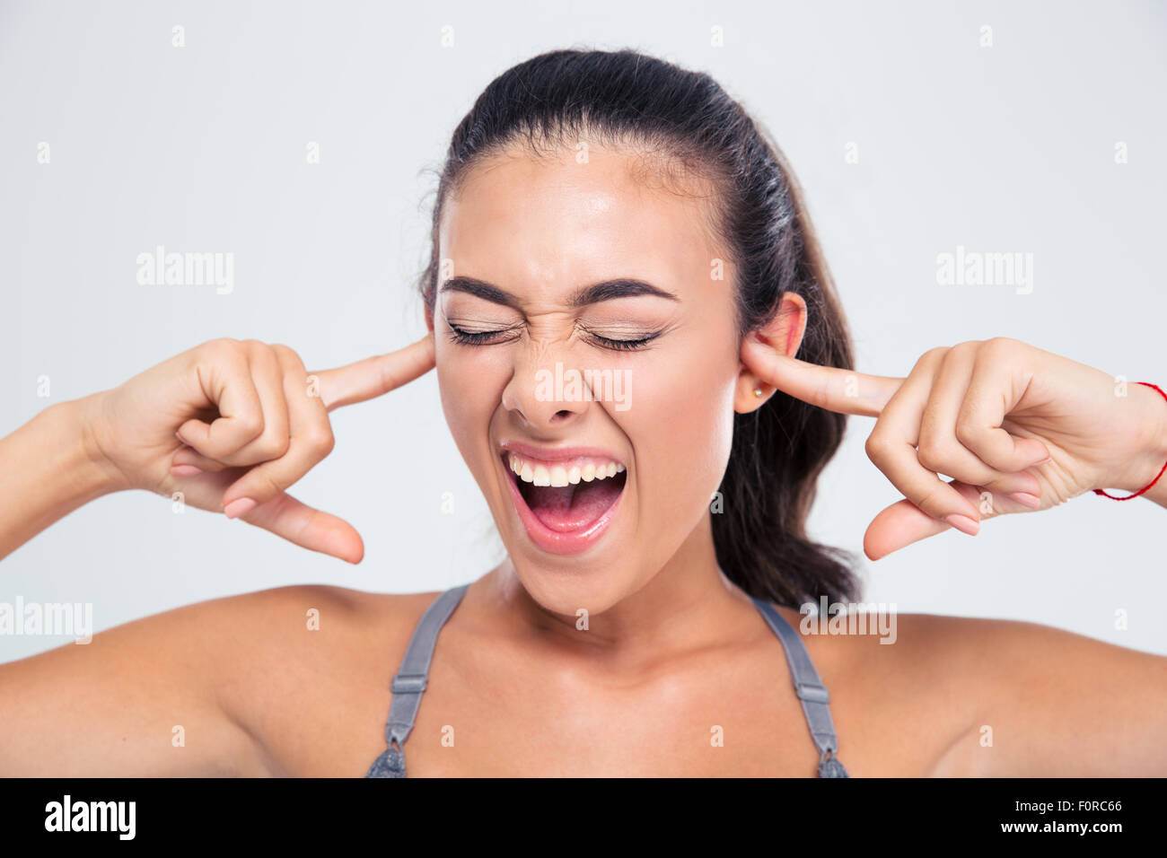 Portrait of a fitness woman covering her ears with fingers and shouting