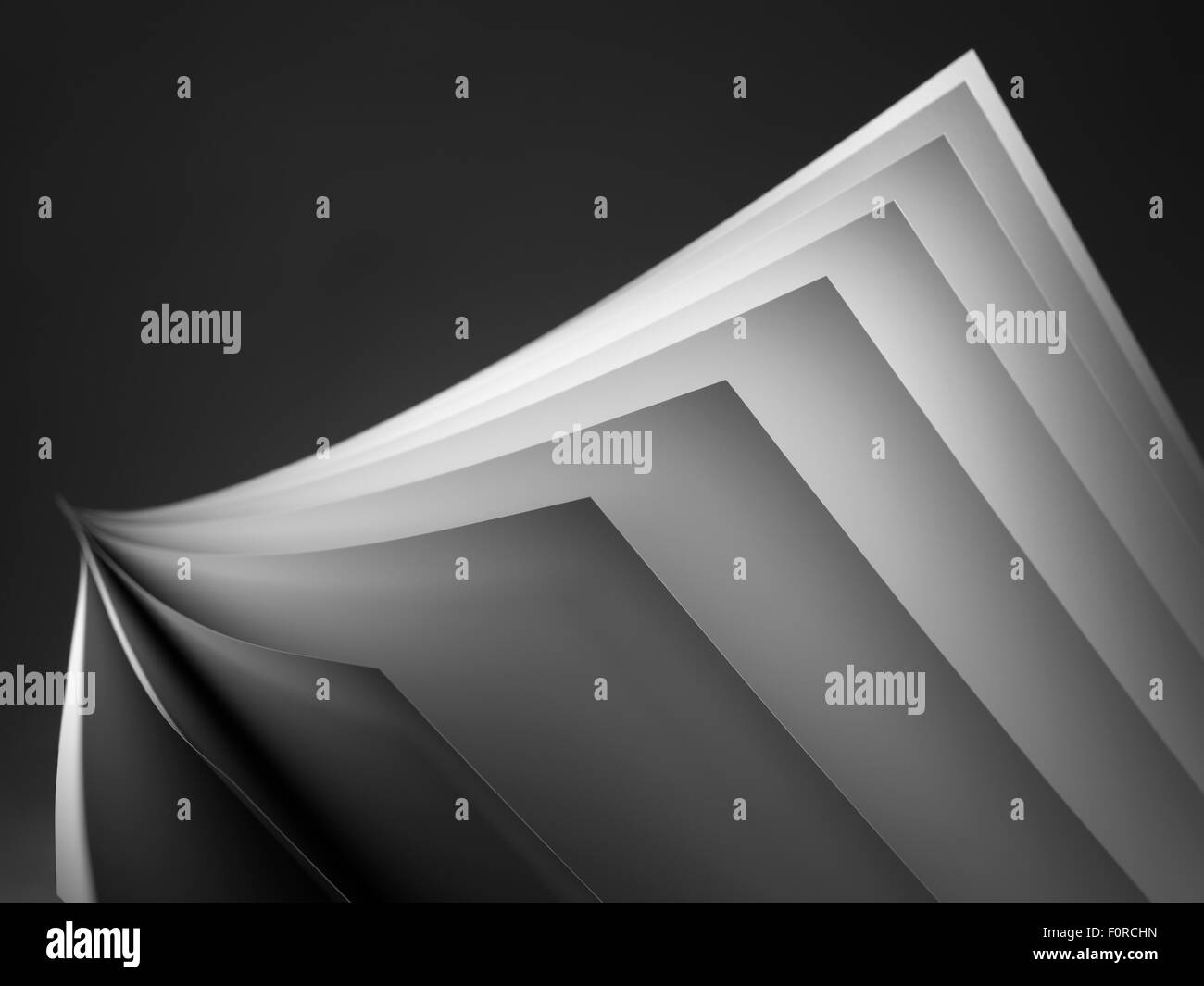 Close up shot of white paper fanned out on a black background with a shallow depth of field and copy space for the designer. Stock Photo