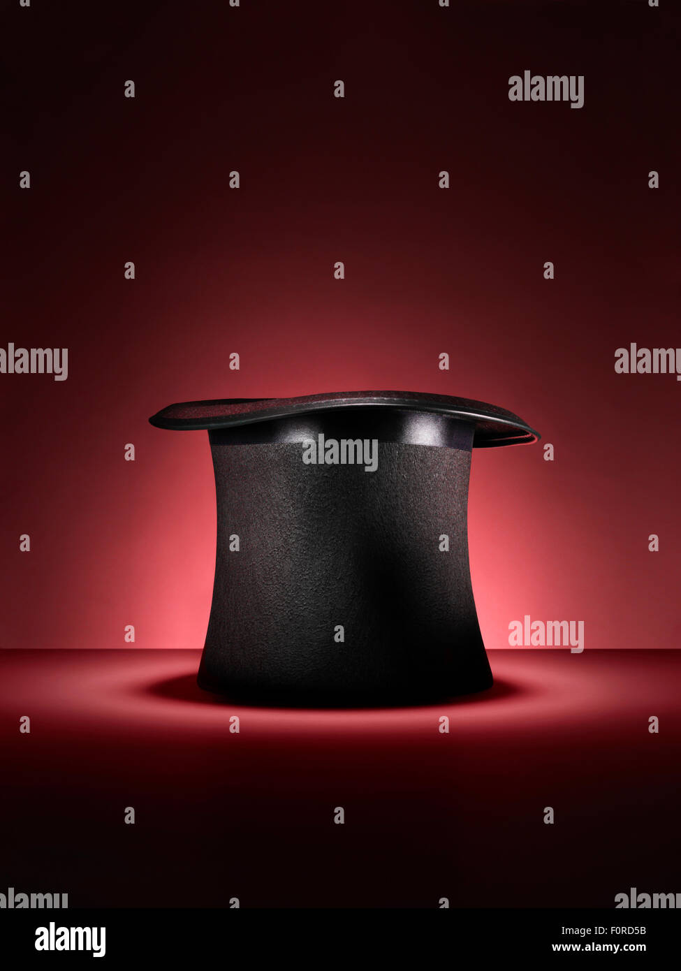 Shot of a traditional magicians style top hat set up for a trick or illusion on a red background with space left for the designe Stock Photo