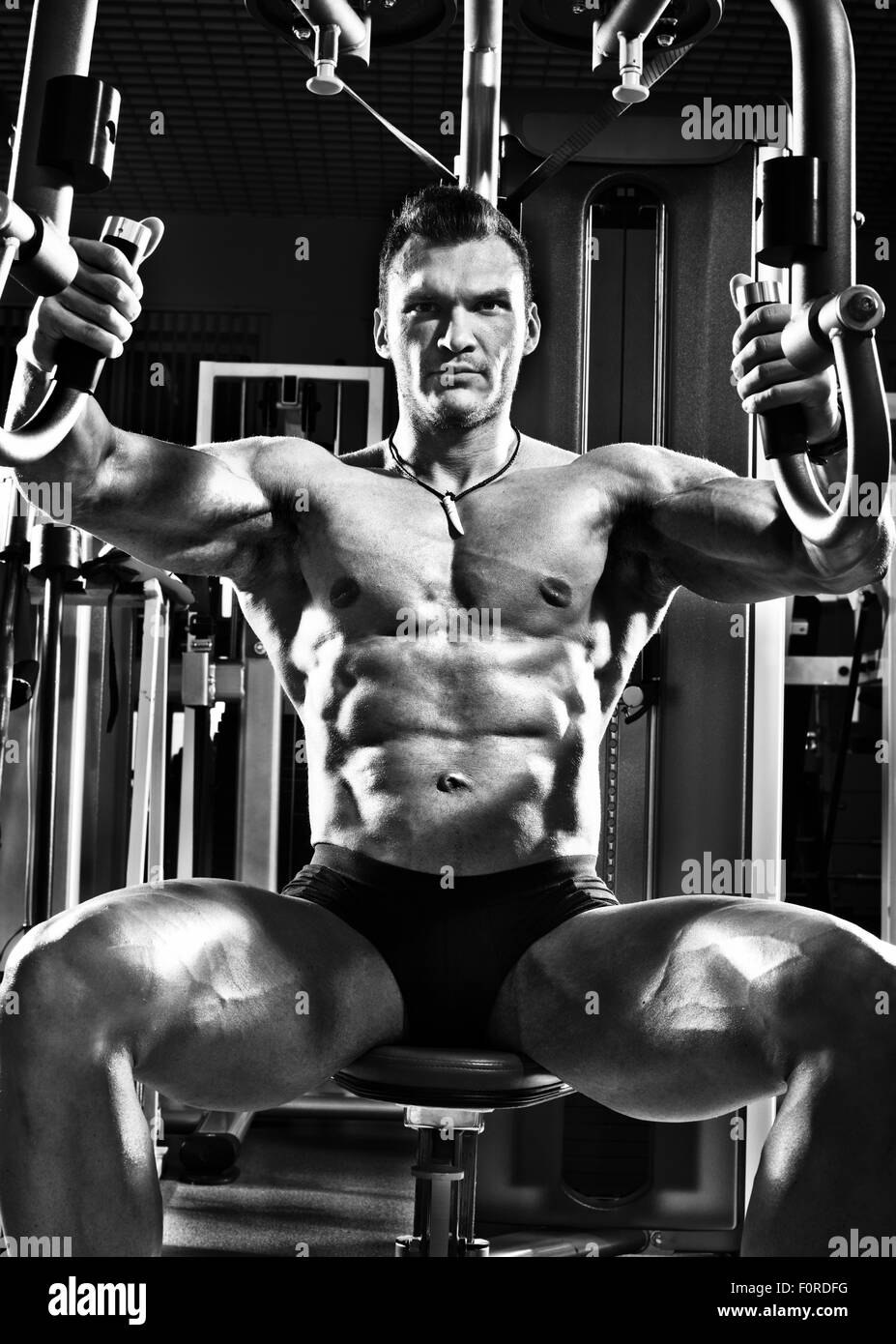 very brawny guy bodybuilder ,  execute exercise  on gym apparatus Butterfly Machine, in gym. Black-and-white photo Stock Photo