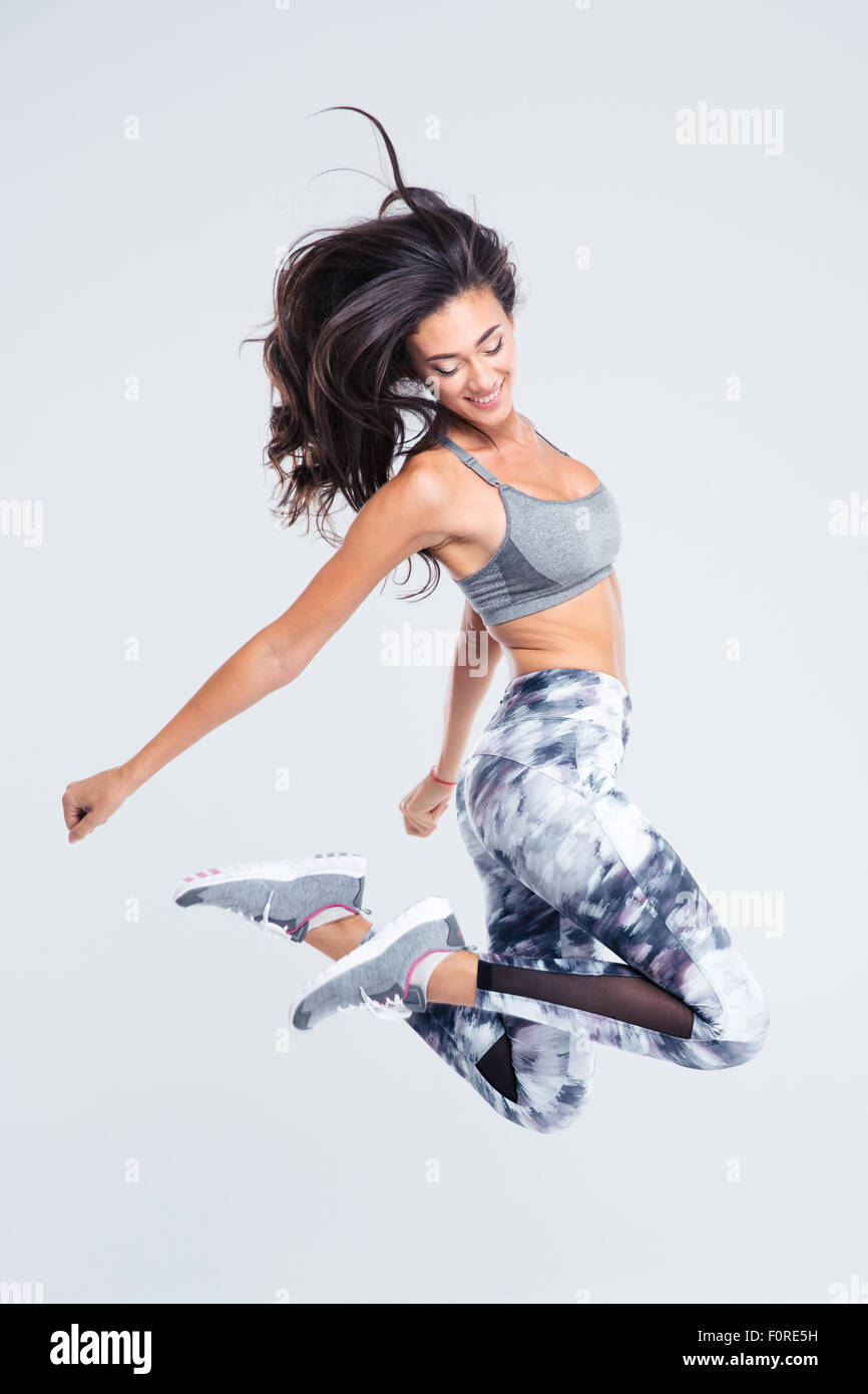 Full length portrait of smiling sports woman jumping isolated on a ...