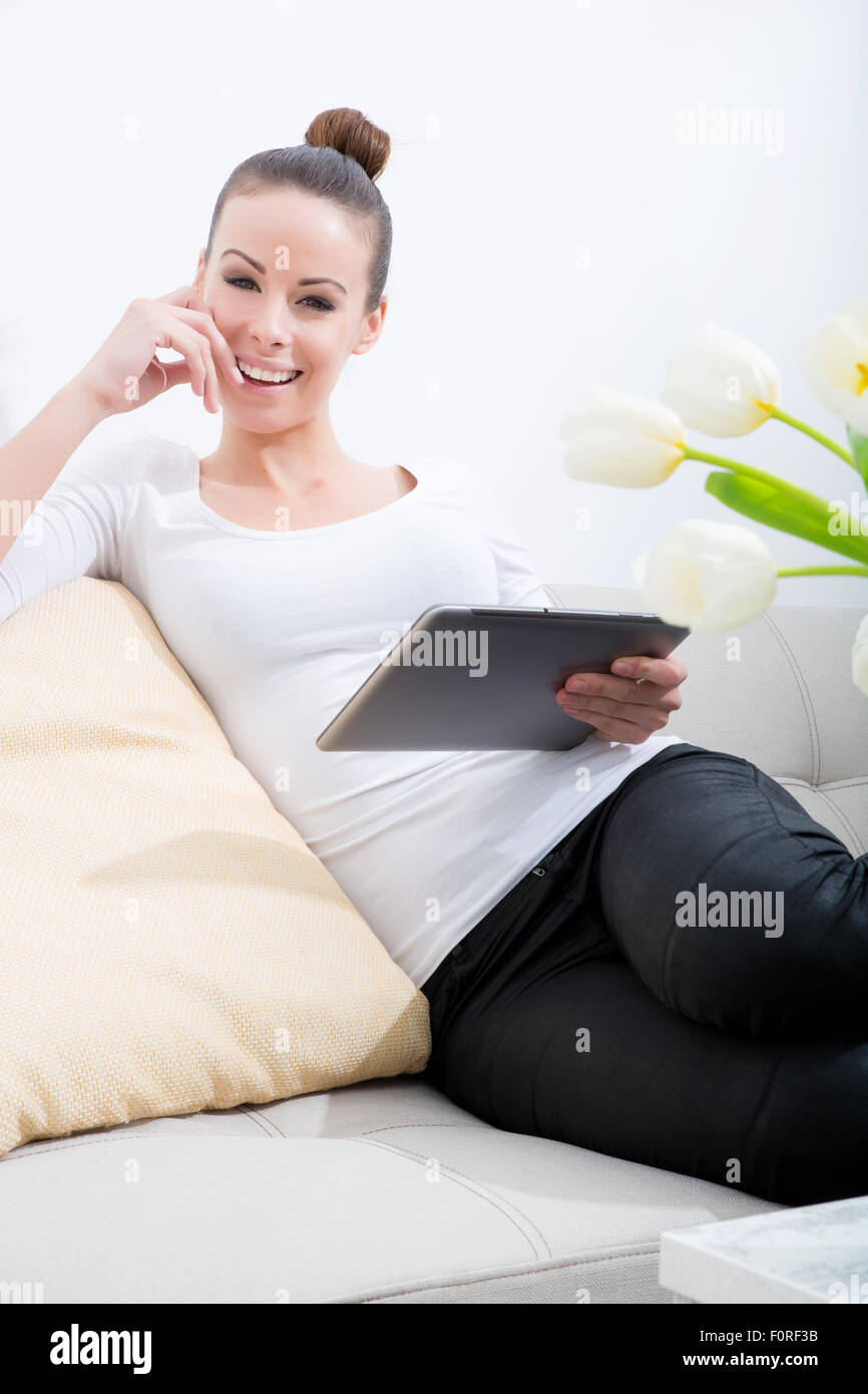 A young woman sitting on the sofa holding a tablet Stock Photo - Alamy