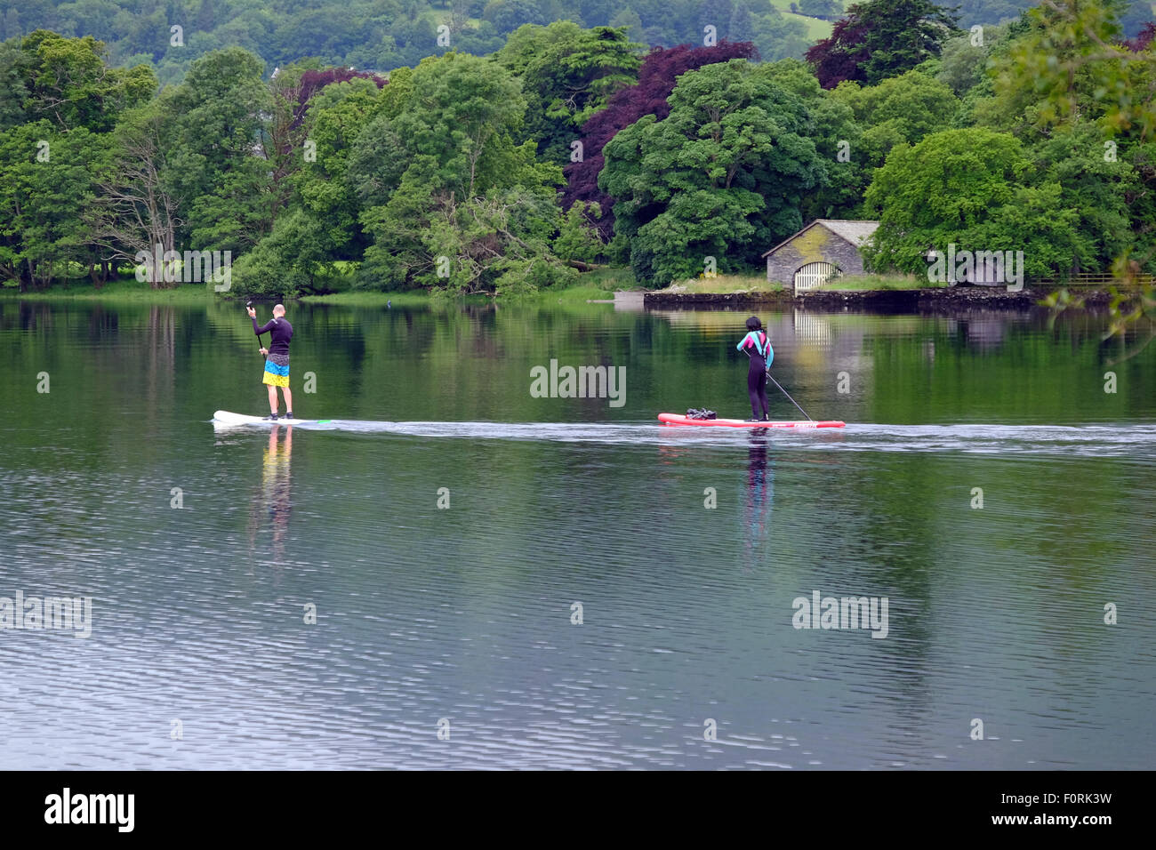 Two people on stand up paddleboards on Conniston Water in the Lake District, UK Stock Photo