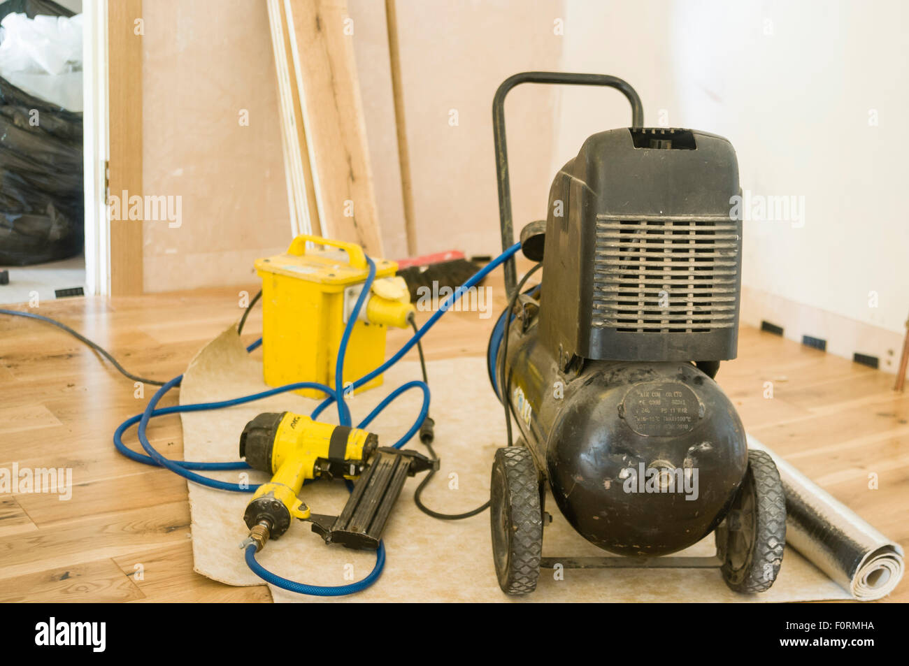 A Compressor And Nail Gun In A Room Where A Wooden Floor Is