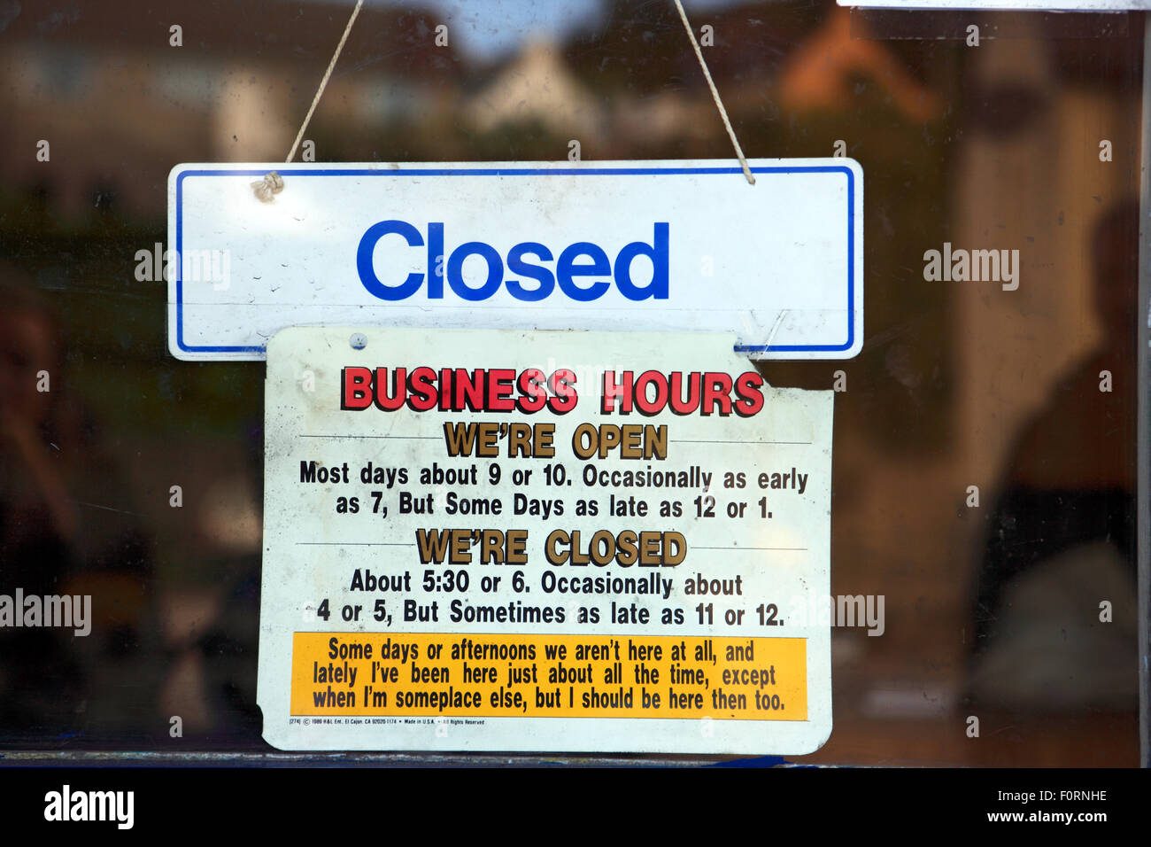 Amusing business hours notice hanging on a shop door in the west coast of Scotland village of Tarbert. Stock Photo