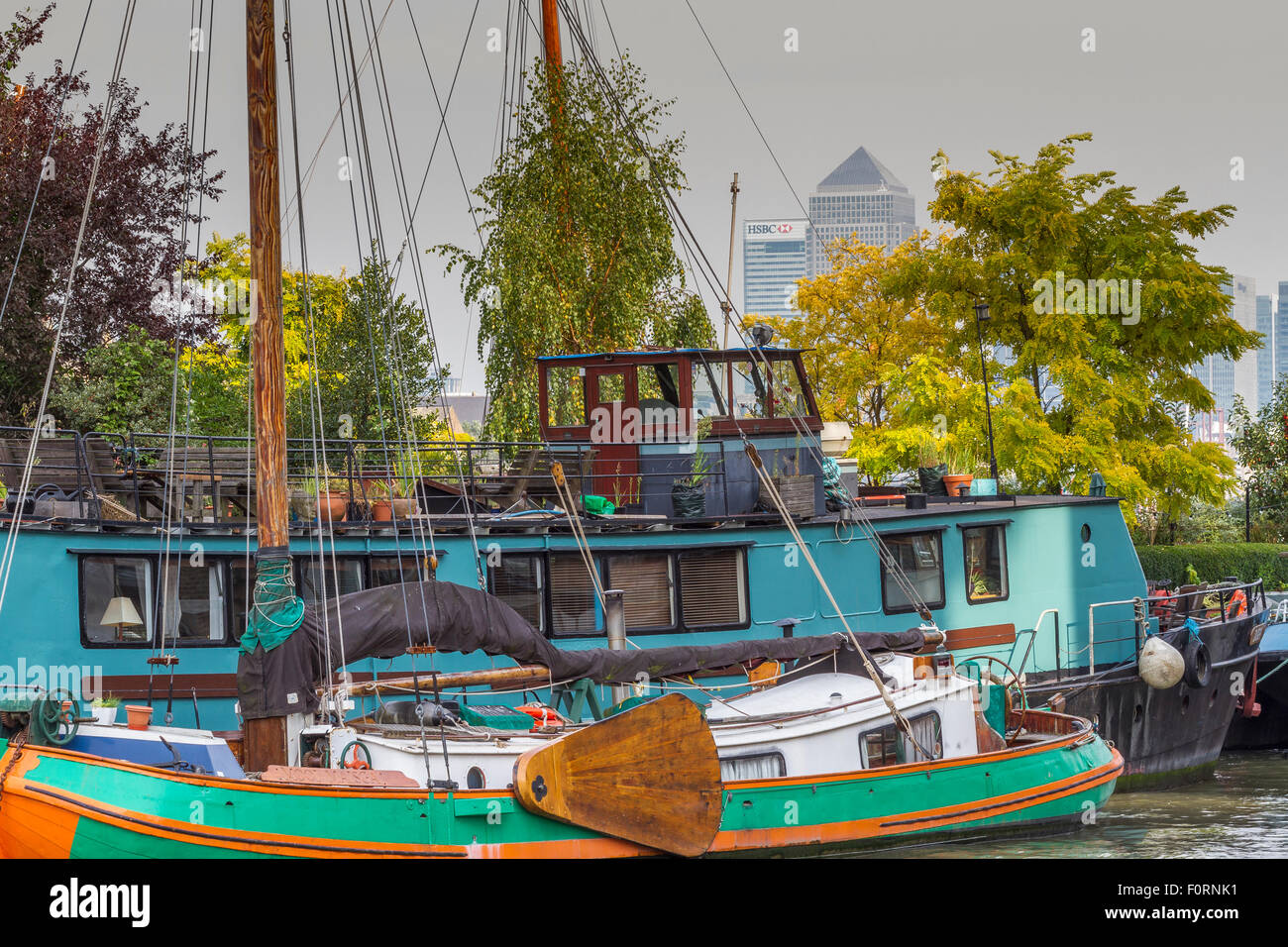 A Houseboat  on The River Thames near Bermondsey with Canary Wharf , including one Canada Square in the distance ,London, UK Stock Photo