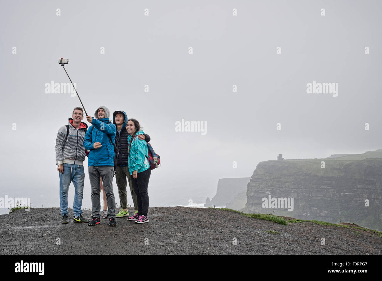 Group of people taking a selfie with a selfie stick at the Cliffs of Moher in Ireland Stock