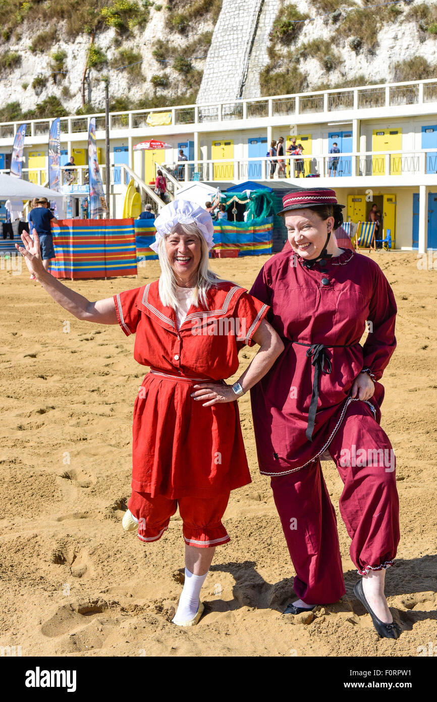 Two women wearing traditional Victorian bathing costumes on the beach at Viking Bay in Broadstairs, Kent. Stock Photo