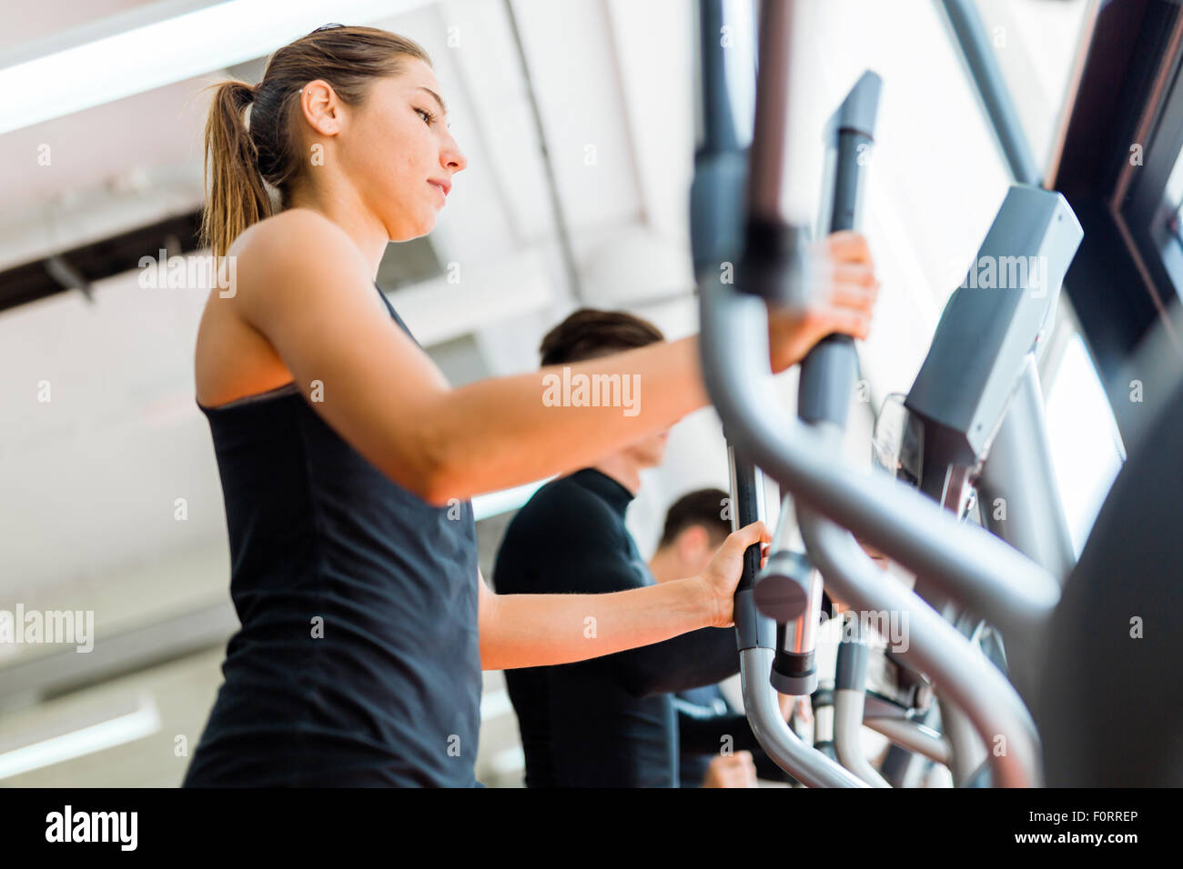 Beautiful fit young woman working out on a stepper together with her friends Stock Photo