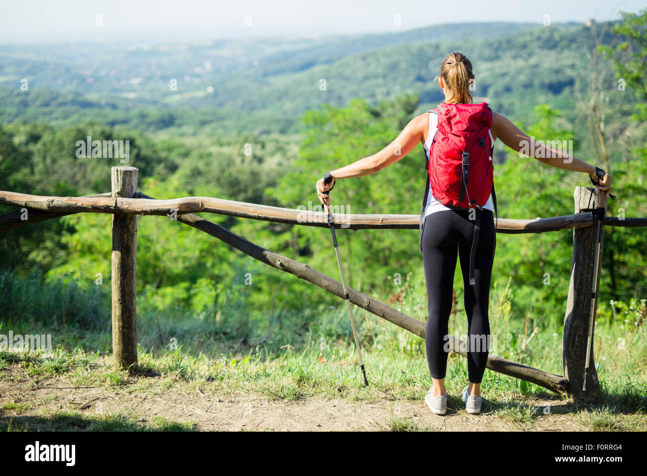 Beautiful hiker woman enjoying the view of a stunning green landscape below her Stock Photo