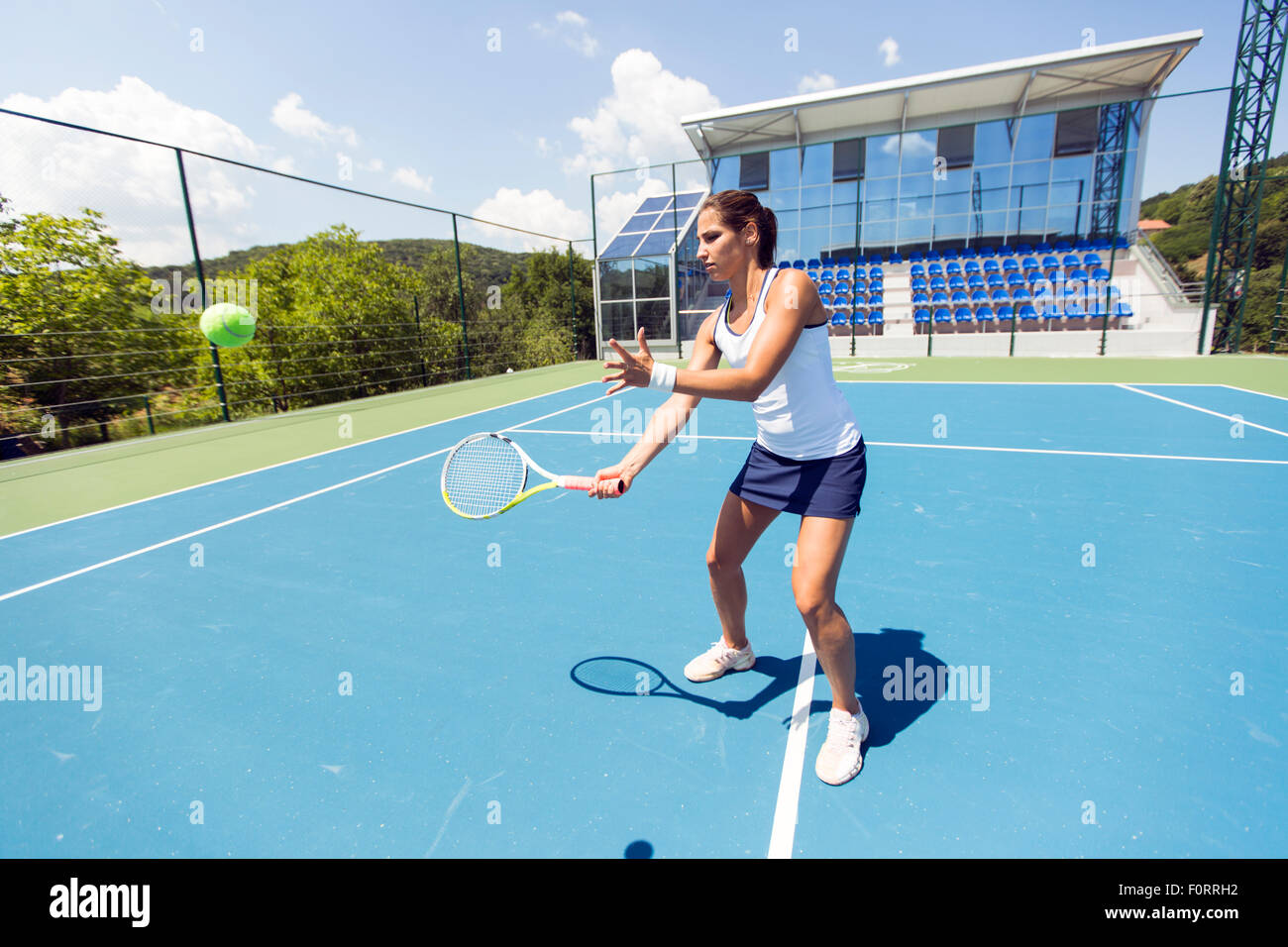 Beautiful female tennis player in action, hitting a forehand Stock Photo