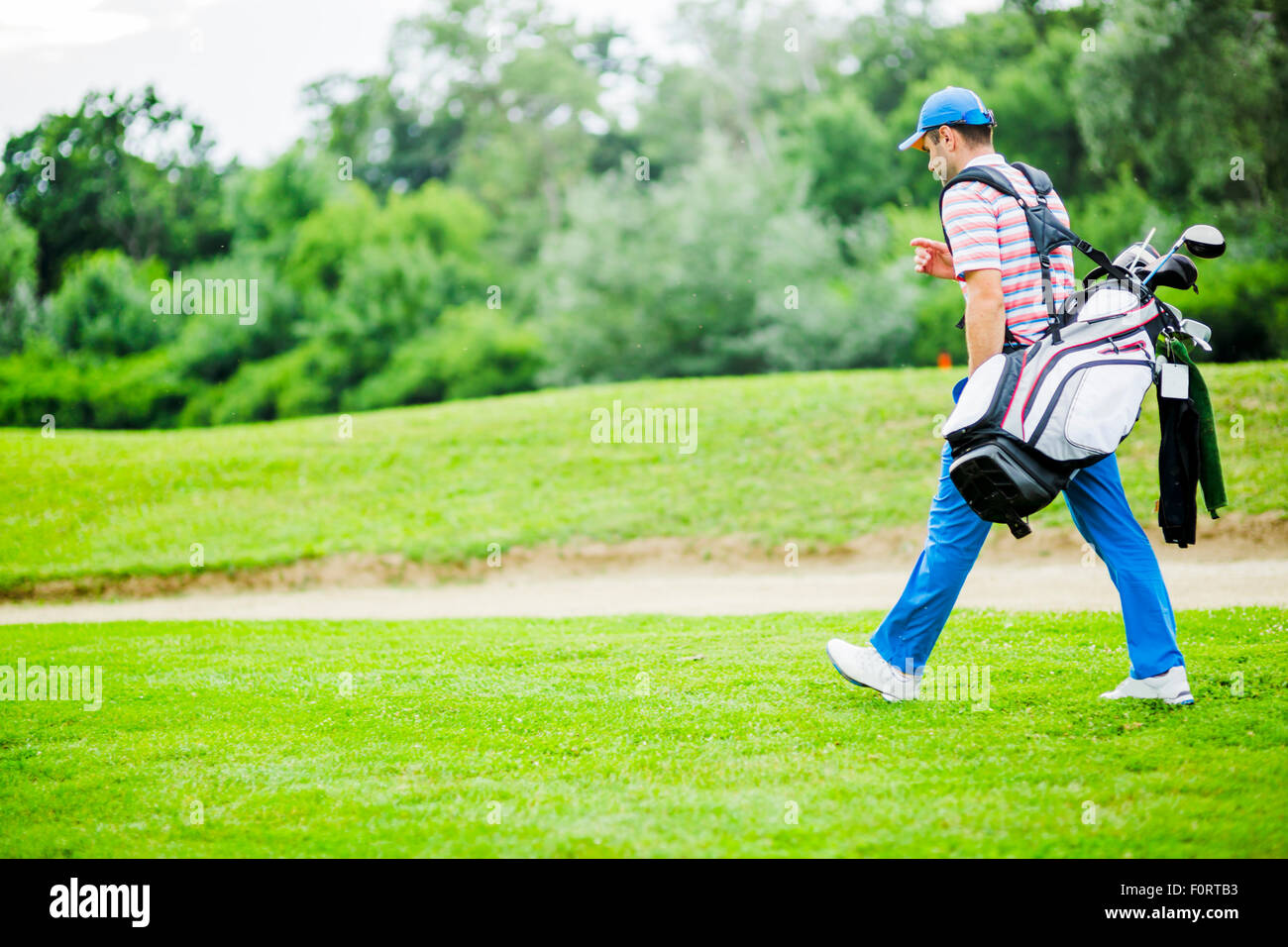 Golfer carrying his equipment on a beautiful sunny day Stock Photo
