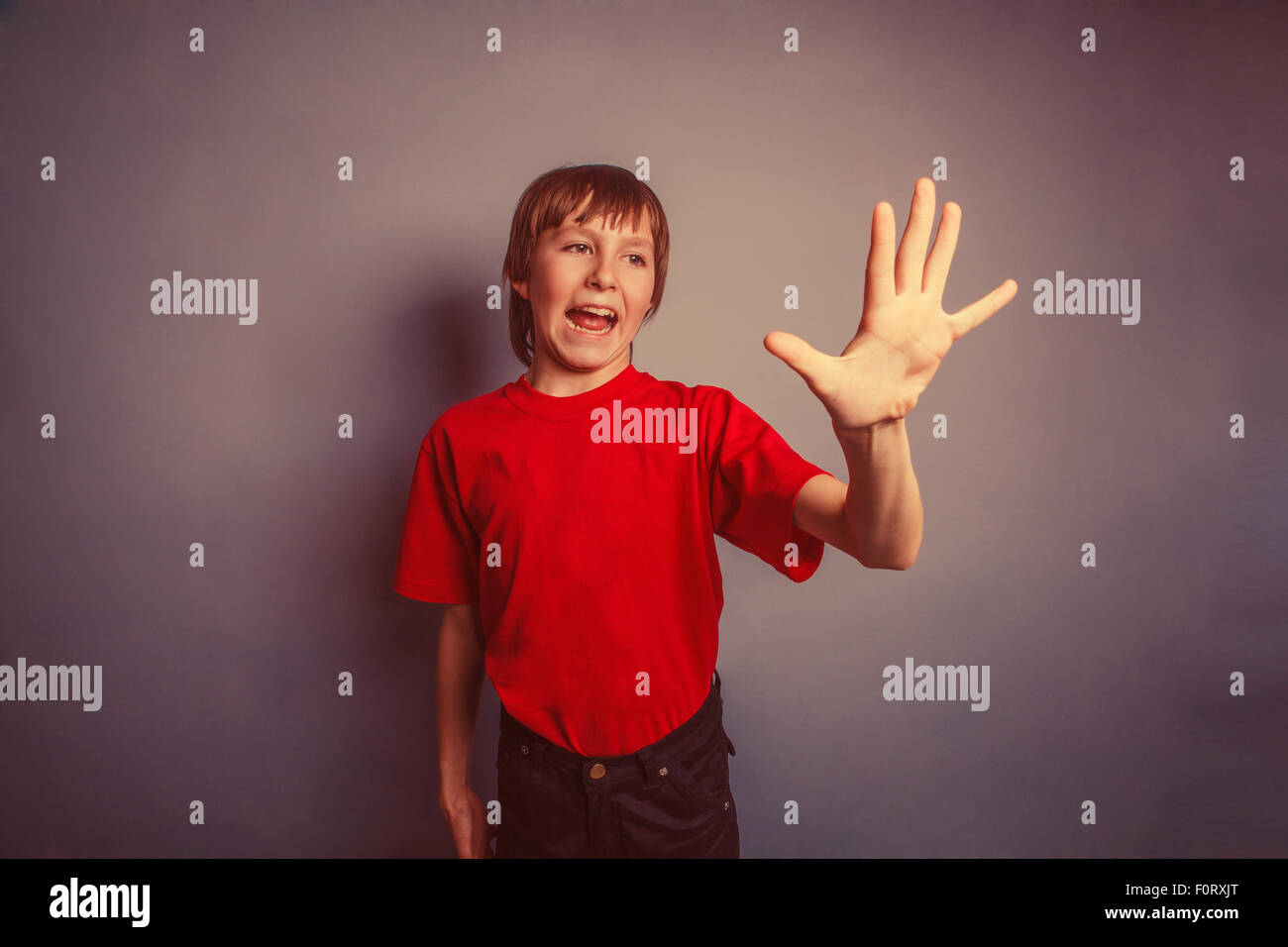 Boy, teenager, twelve years old, in a red shirt, showing a hand Stock