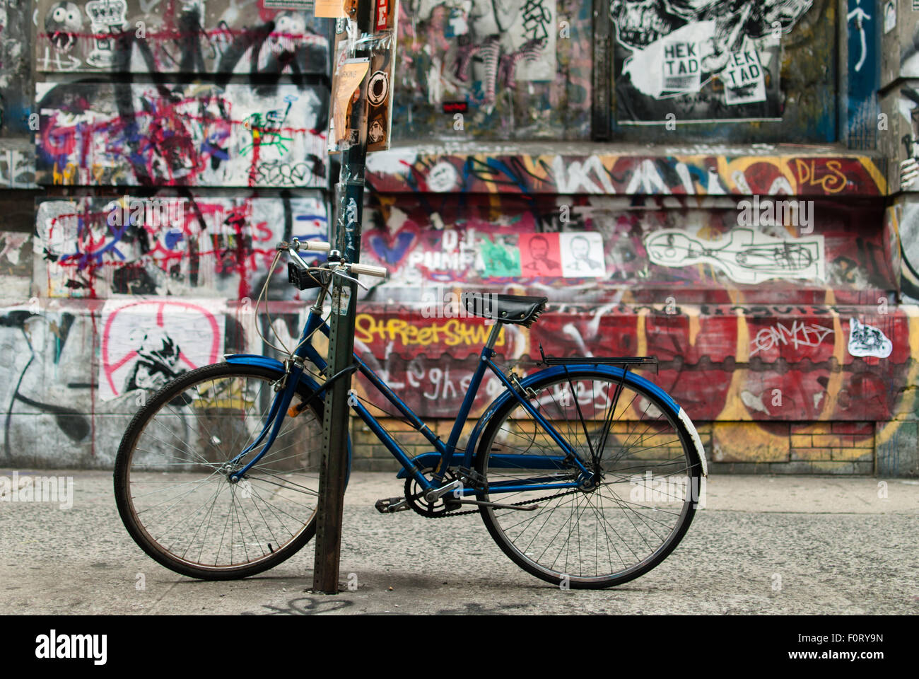 Bicycle locked to post with graffiti background in New York Stock Photo