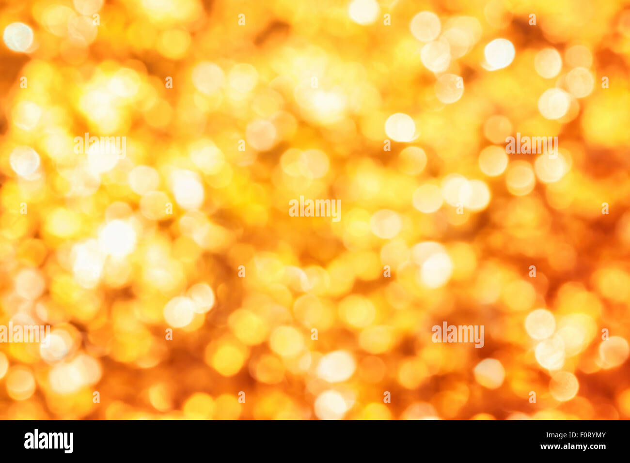 Shining out-of-focus highlights in gold leaves create a bright bokeh composition, ideal as a nature background Stock Photo