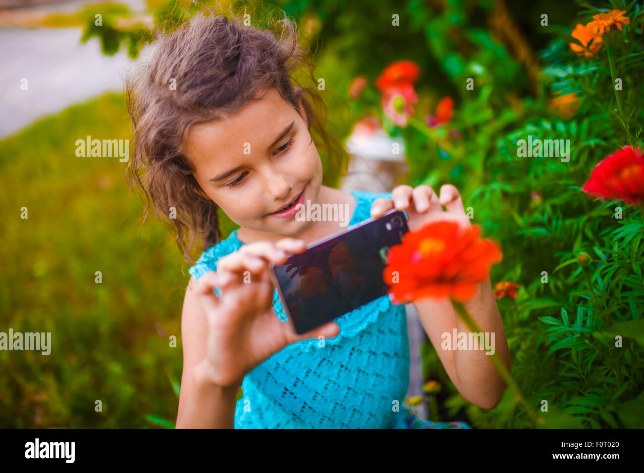 Teenage girl photographing flower phone on a green background in Stock Photo