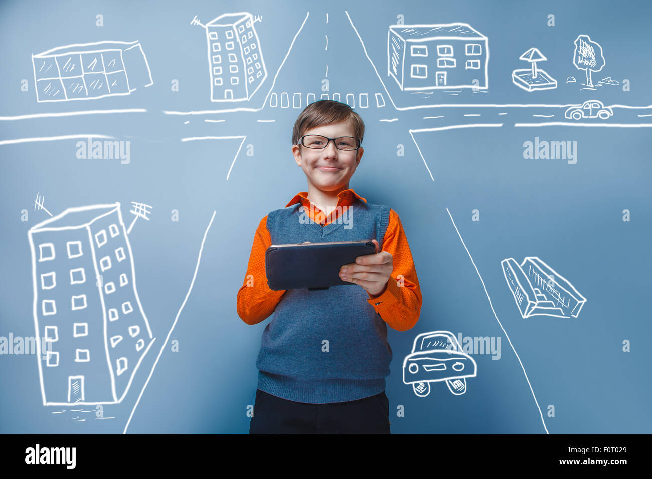 European -looking  boy of ten years in glasses holding tablet in hand on blue background Stock Photo