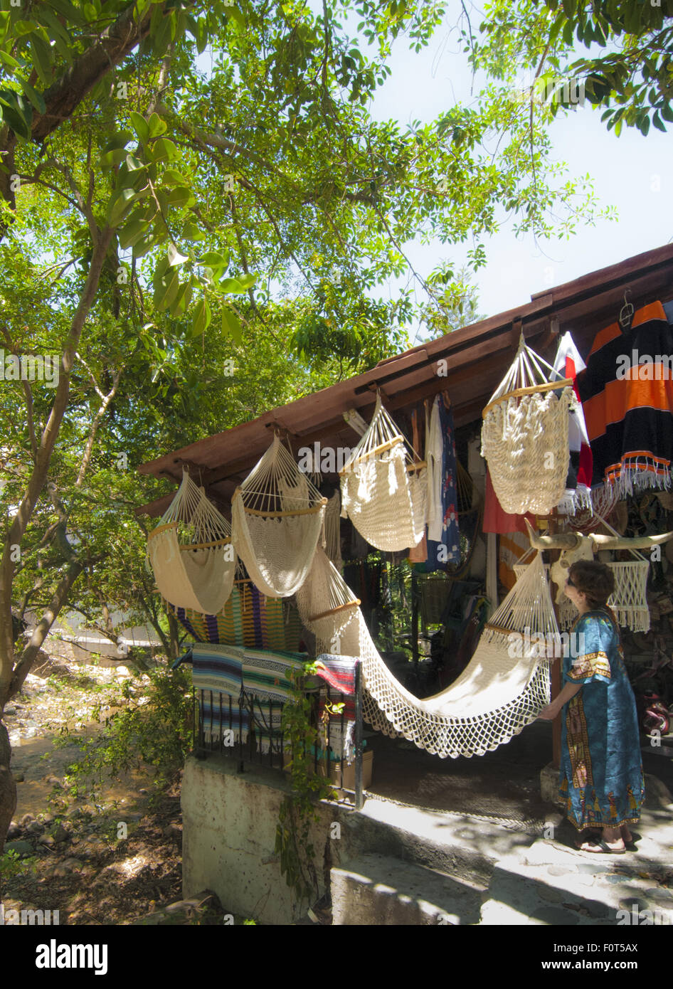 Woman shopper inspects hammocks in a shop on Cuale River Island, a vibrant market place in Puerto Vallarta, Mexico. Stock Photo