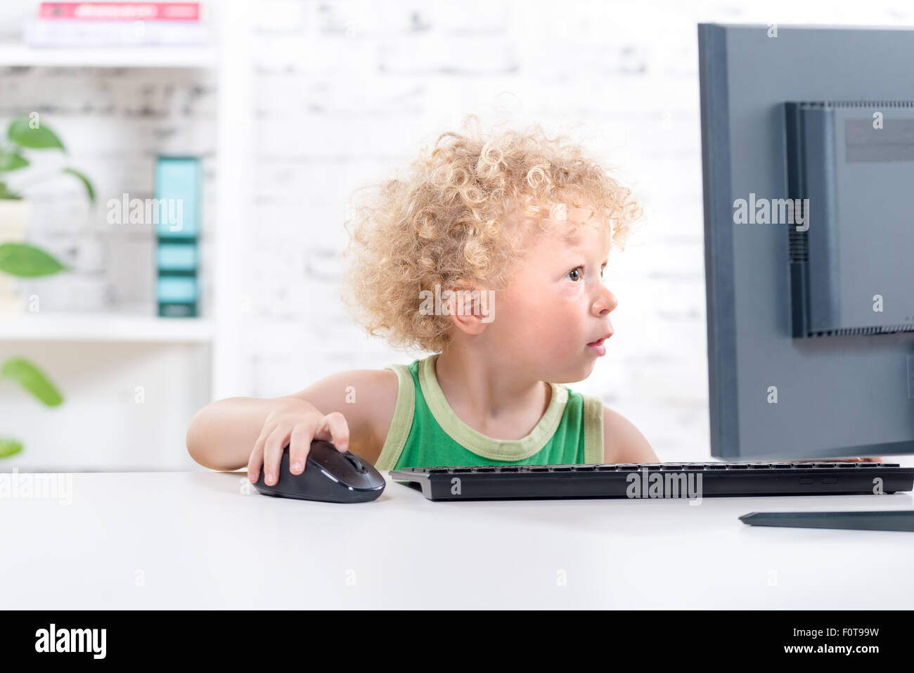 a little blond boy playing with the mouse of a computer Stock Photo - Alamy