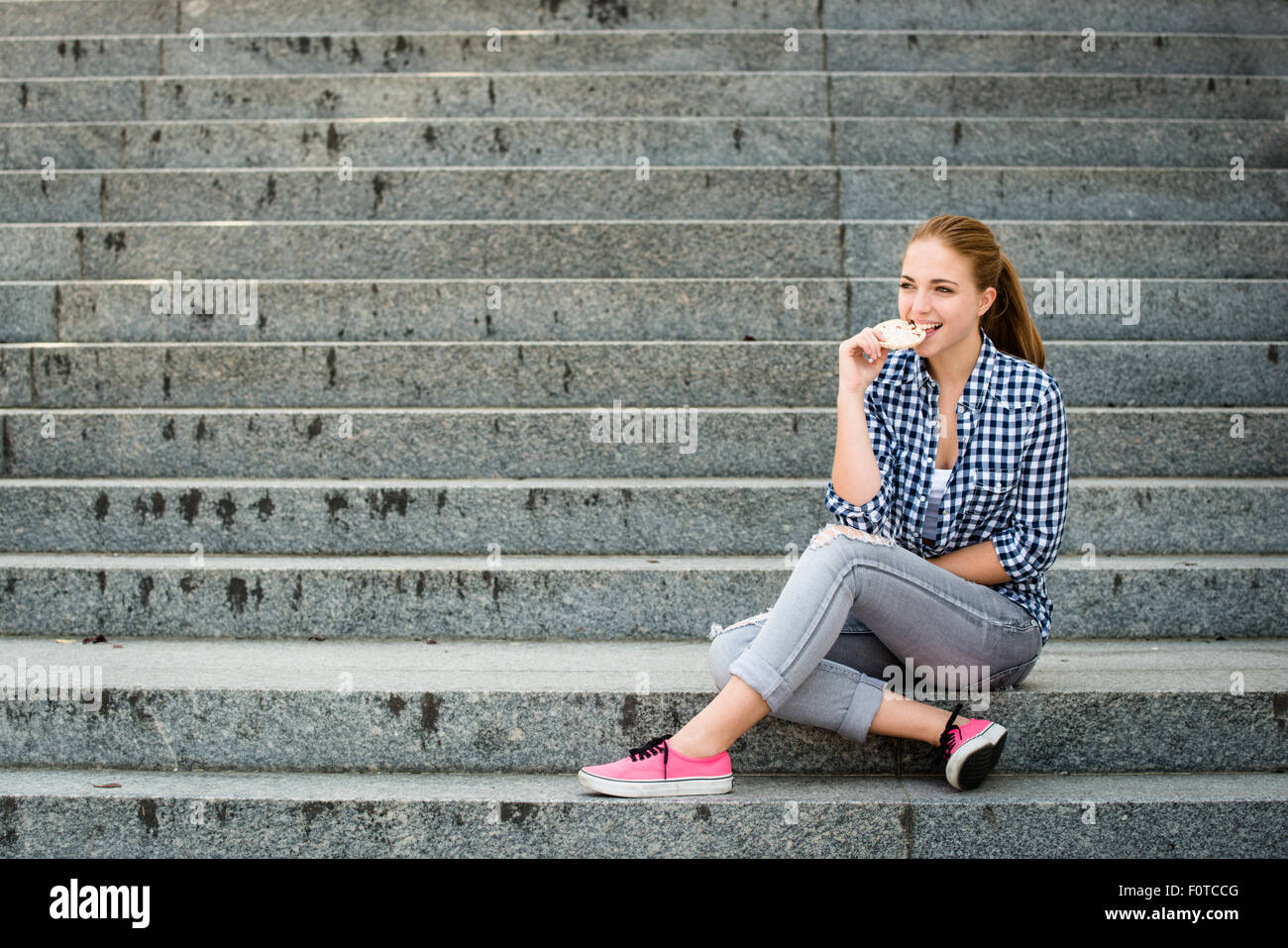 Healthy lifestyle  - teenager eating puffed bread outdoor sitting on stairs Stock Photo