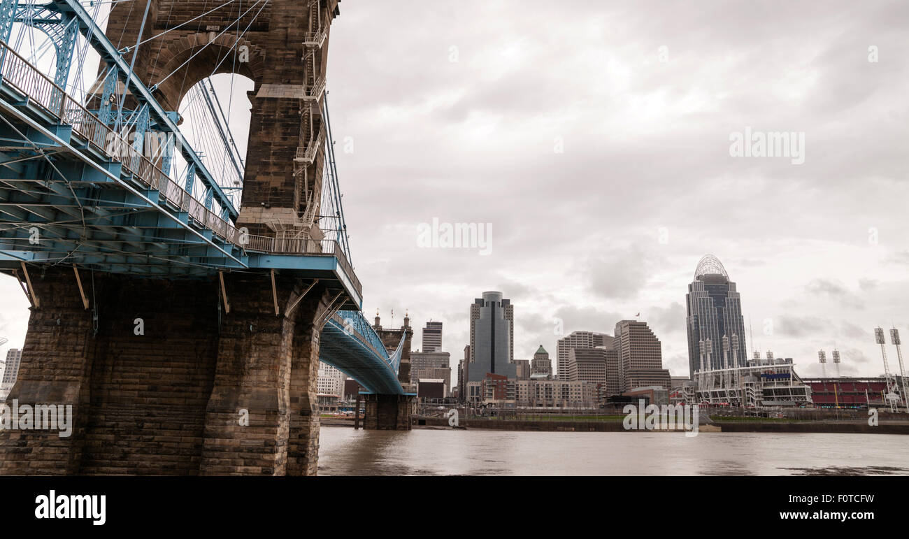 The Ohio River is at flood stage as it passes underneath a historical suspension bridge Stock Photo