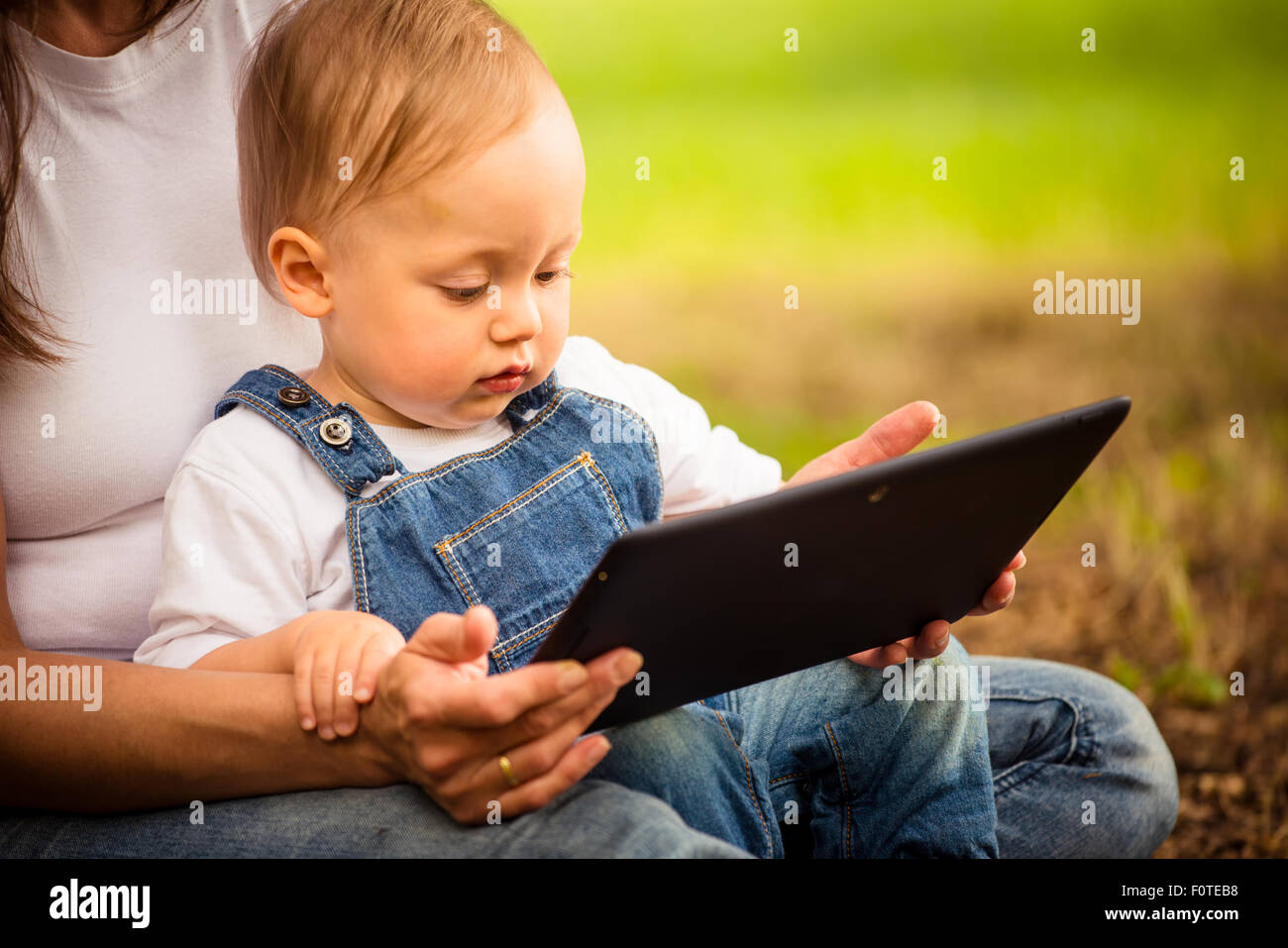 Mother with her baby watching together in tablet computer outdoor Stock Photo