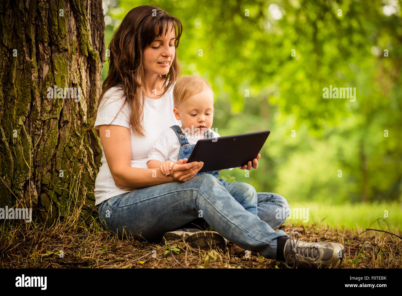Mother with her child watching together in tablet computer outdoor Stock Photo
