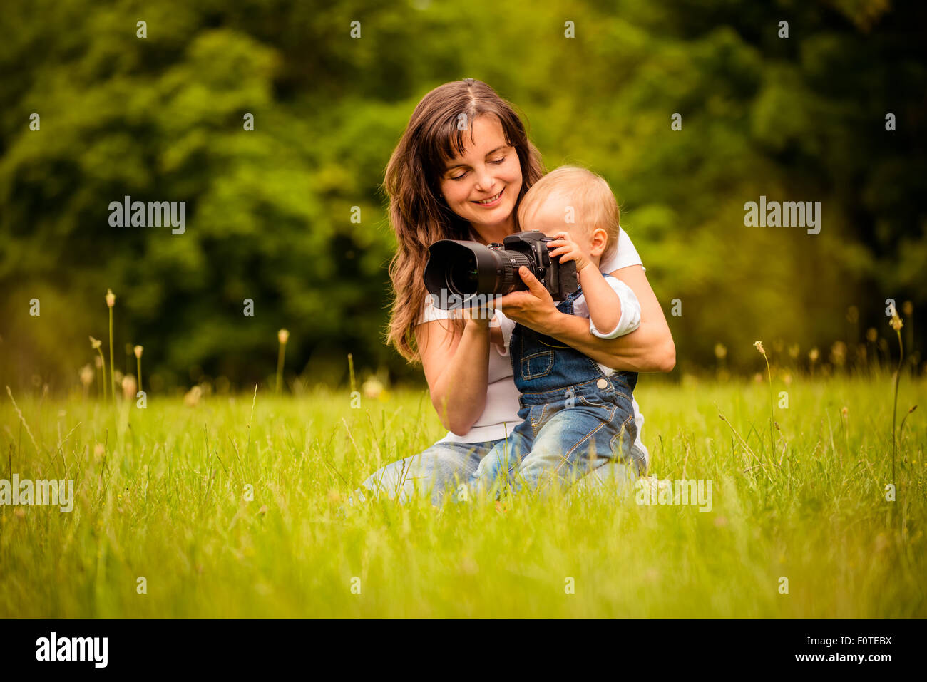 Mother showing her baby photos on DSLR camera outdoors Stock Photo