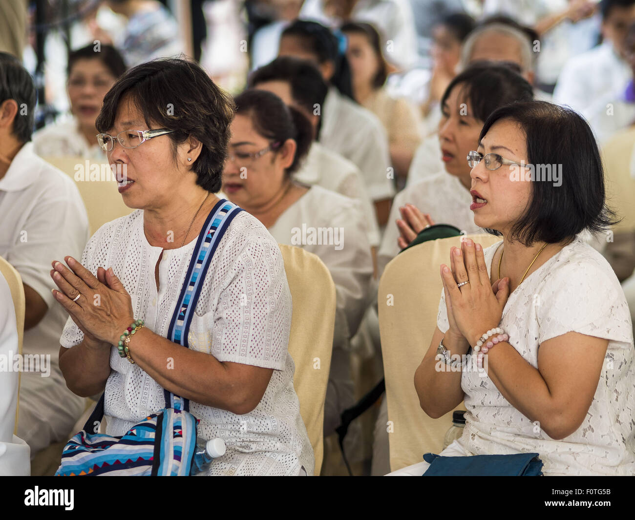 Bangkok, Thailand. 21st Aug, 2015. People pray at a Buddhist ceremony at Central World to honor the dead from the Erawan Shrine bombing. The Bangkok Metropolitan Administration (BMA) held a religious ceremony Friday for the Ratchaprasong bomb victims. The ceremony started with a Brahmin blessing at Erawan Shrine, which was the target of a bombing Monday night. After the blessing people went across the street to the plaza in front of Central World mall for an interfaith religious service. Credit:  ZUMA Press, Inc./Alamy Live News Stock Photo