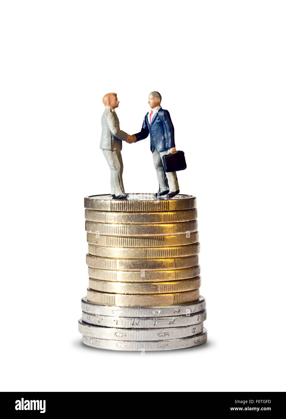 Miniature handshake euro coin tower, macro shot of business men figurines shaking hands on top of tower made of one and two euro Stock Photo