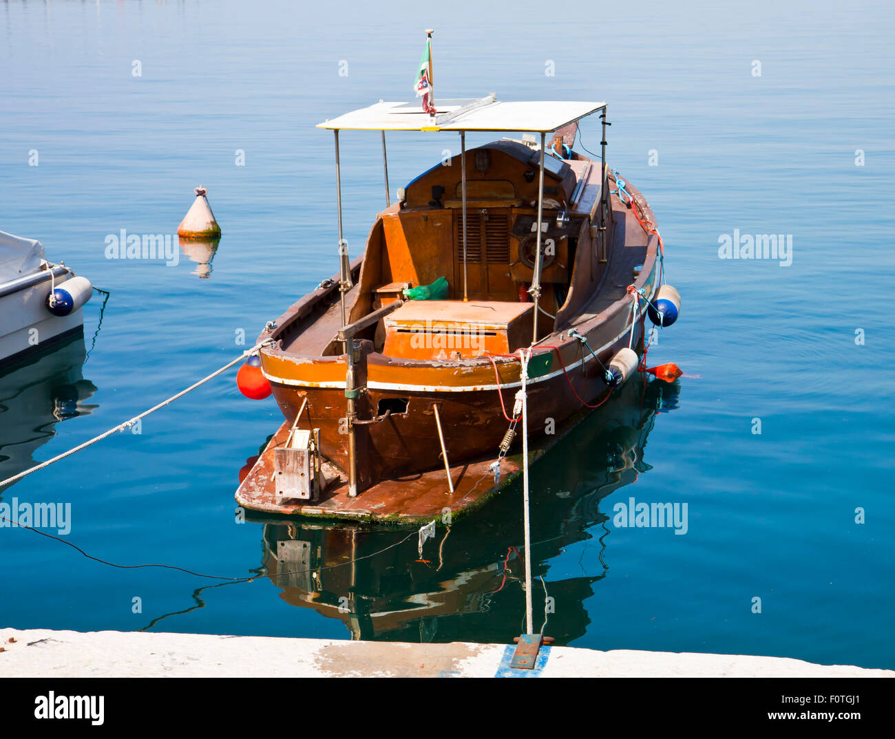 Picturesque old wooden boat with sunshade roof moored at the pier with ...