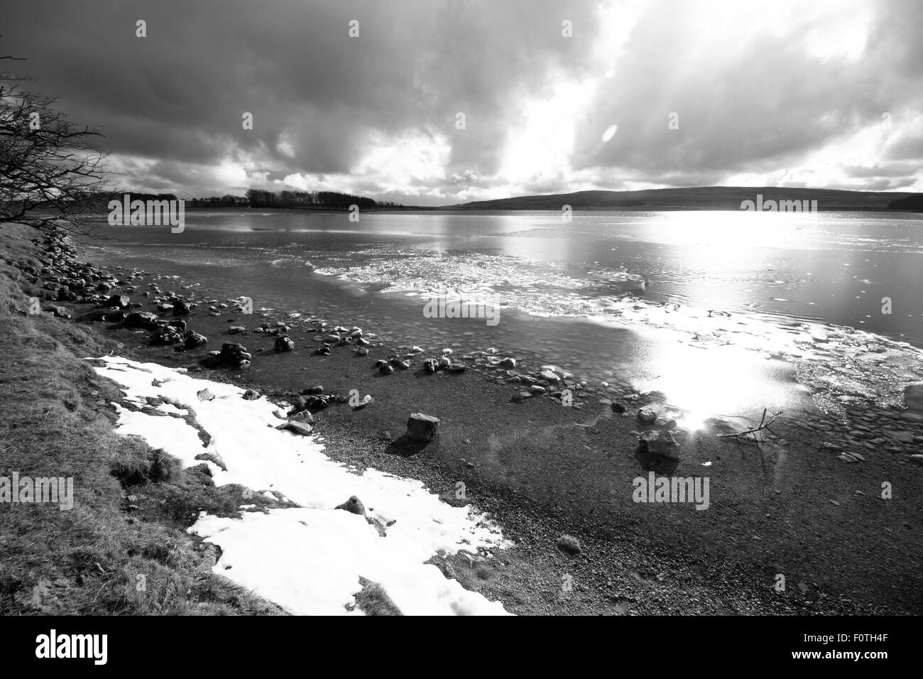 A dramatic sky reflected in the waters of Malham Tarn in North Yorkshire, England, UK, with snow and ice during winter. Stock Photo