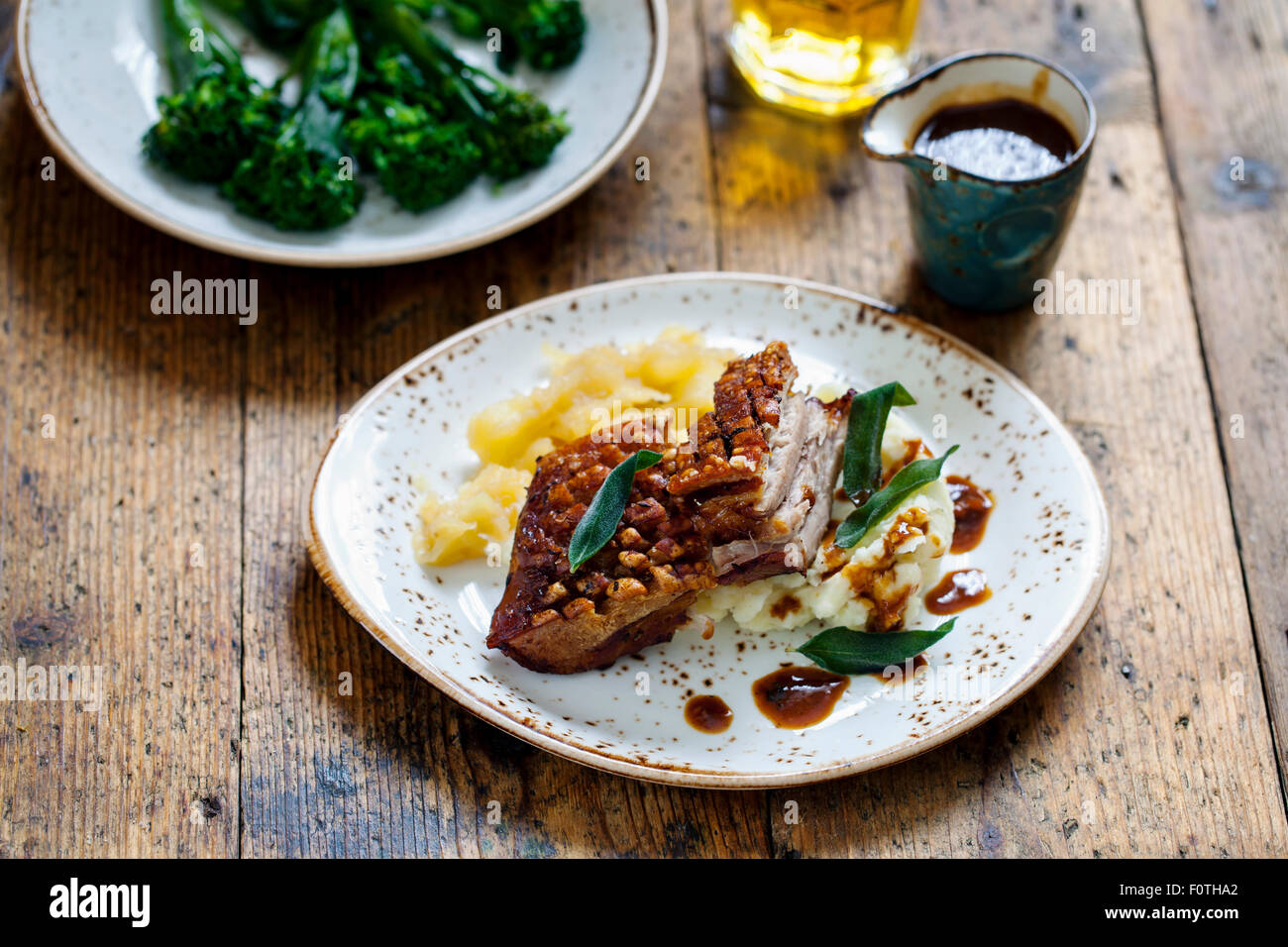Pork belly with crackling, mashed potatoes, apple sauce and deep fried sage leaves Stock Photo