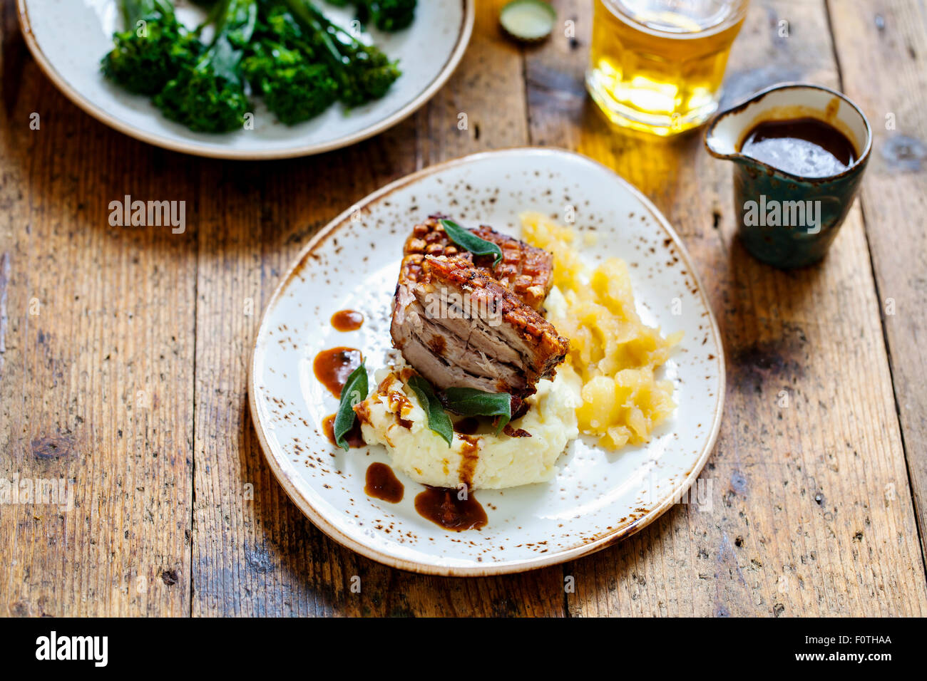 Pork belly with crackling, mashed potatoes, apple sauce and deep fried sage leaves Stock Photo