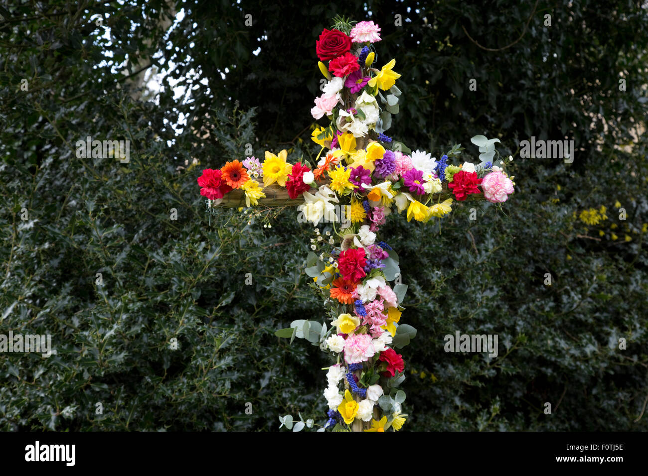 Easter cross covered in colourful flowers outside Cotswold church UK Stock Photo