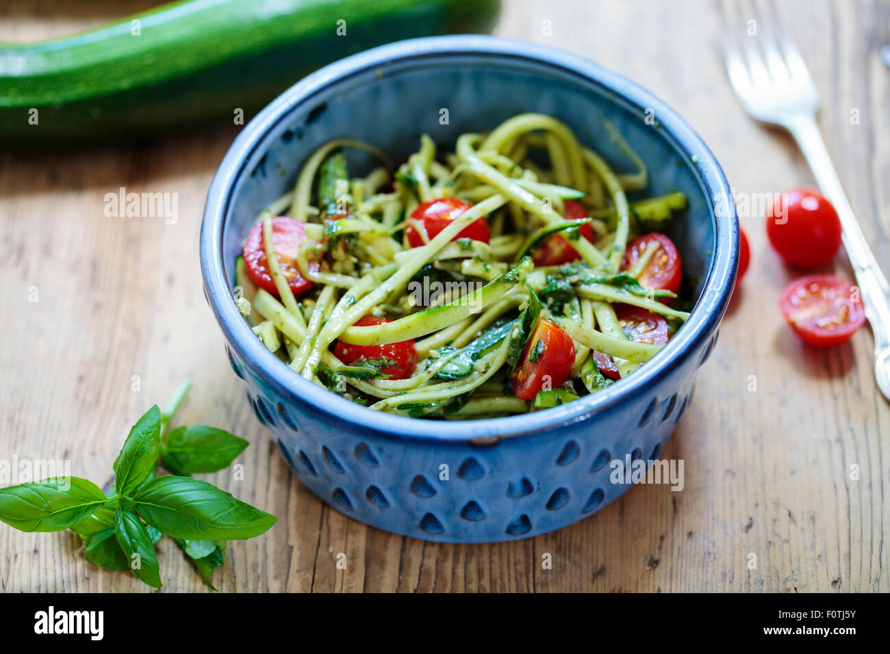 Zucchini spaghetti with cherry tomatoes and basil pesto Stock Photo Alamy