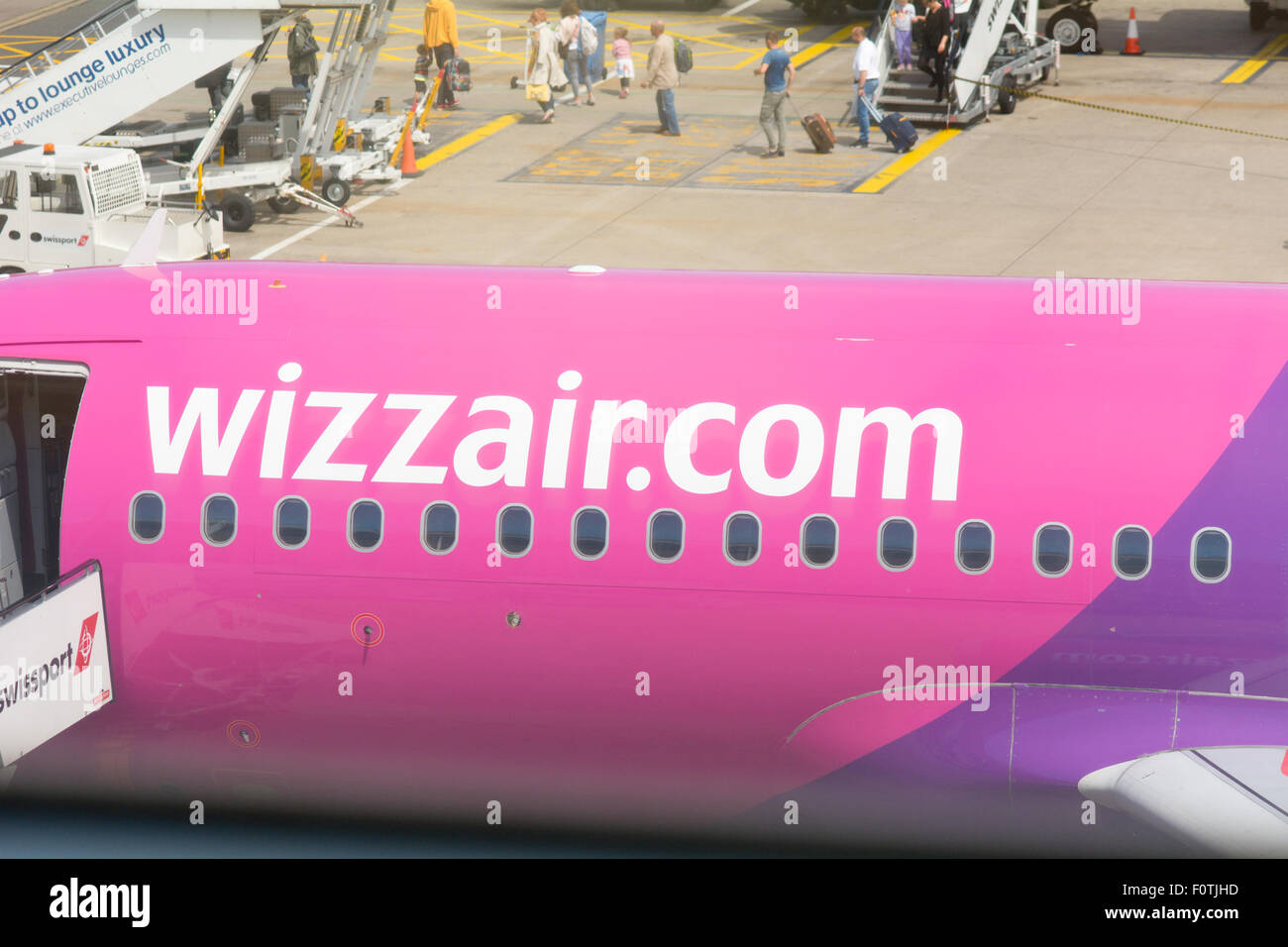 Wizzair.com plane on the ground at Luton Airport with passengers disembarking from plane behind in Luton, Bedfordshire, England Stock Photo
