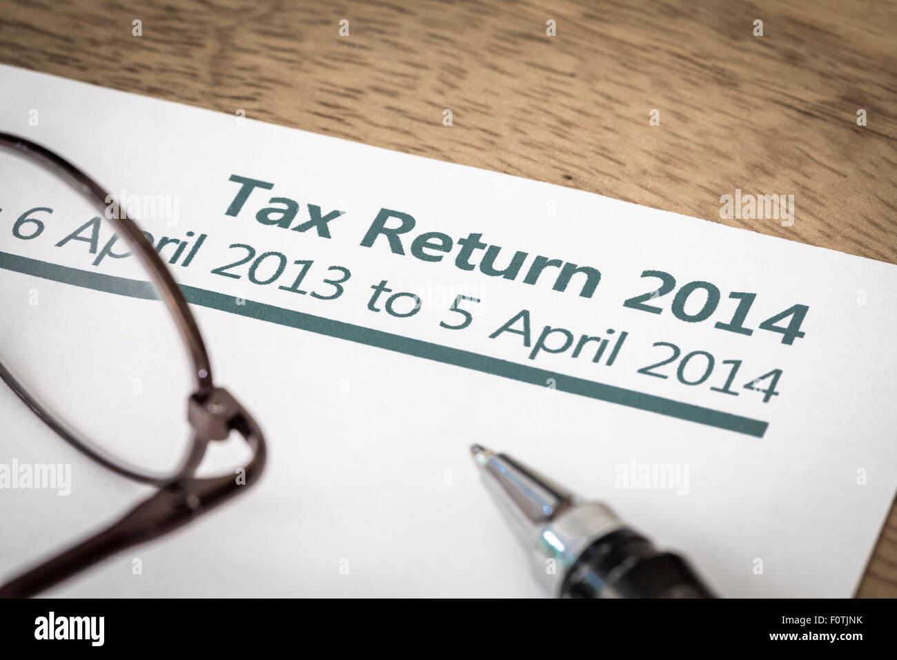 UK Income tax return form for 2014 on a desk with pen and glasses Stock Photo