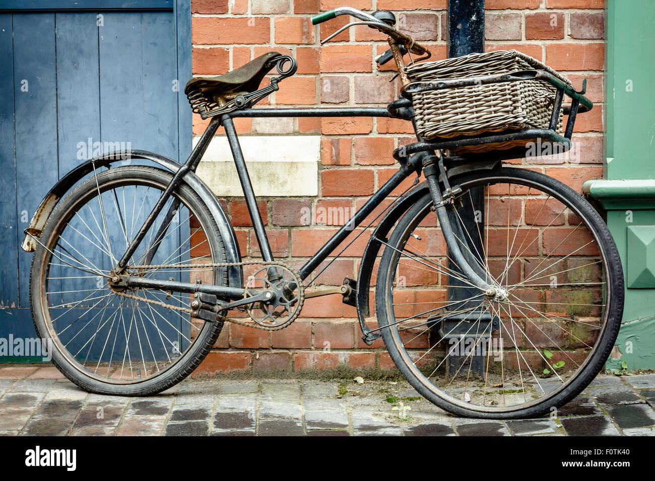 Old retro cycle with basket leaning against a brick wall Stock Photo