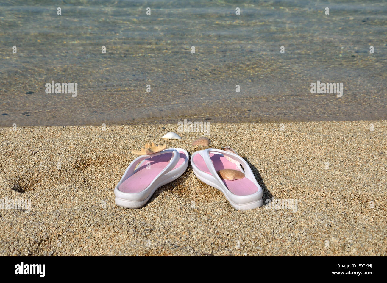 White-pink flip flops on beach with sea in background Stock Photo - Alamy